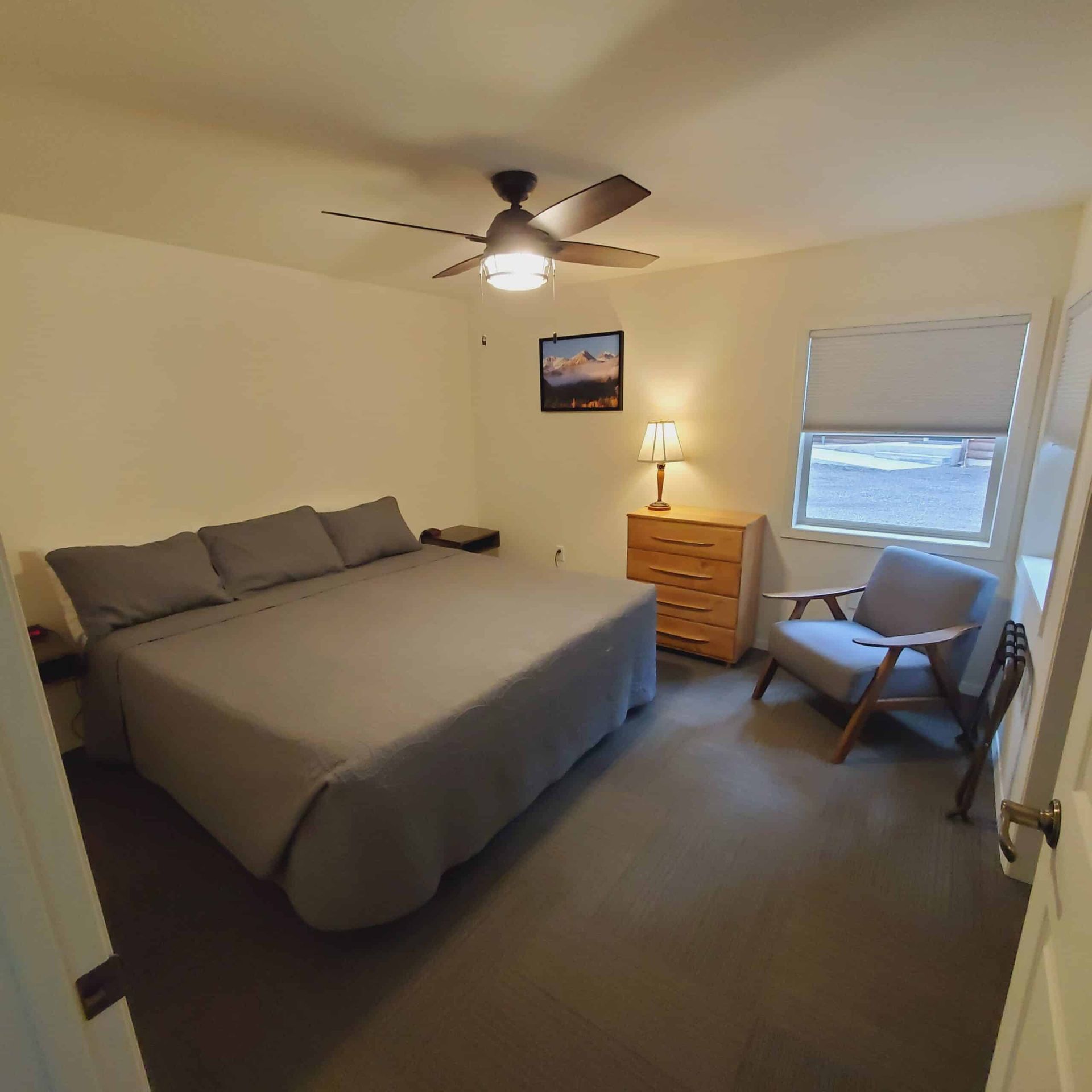 A bedroom with a large bed and a ceiling fan