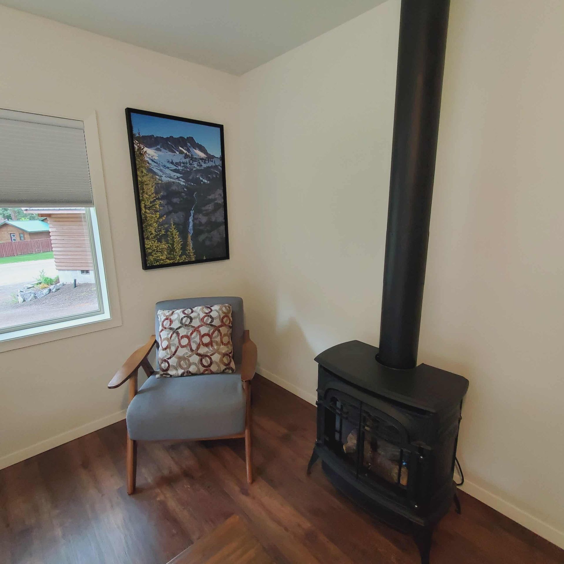 A room with a chair and a stove and a picture on the wall