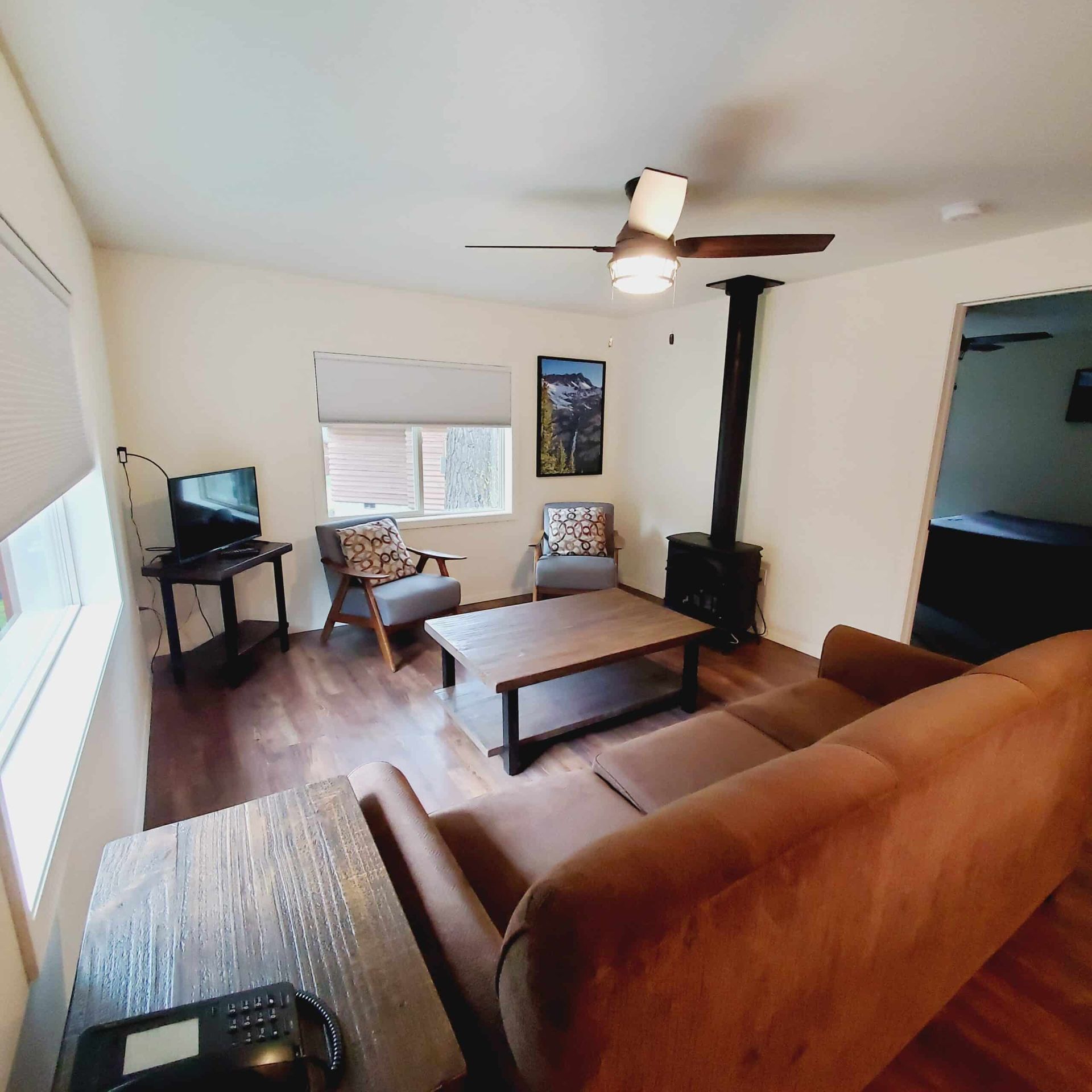 A living room with a couch and chairs and a ceiling fan