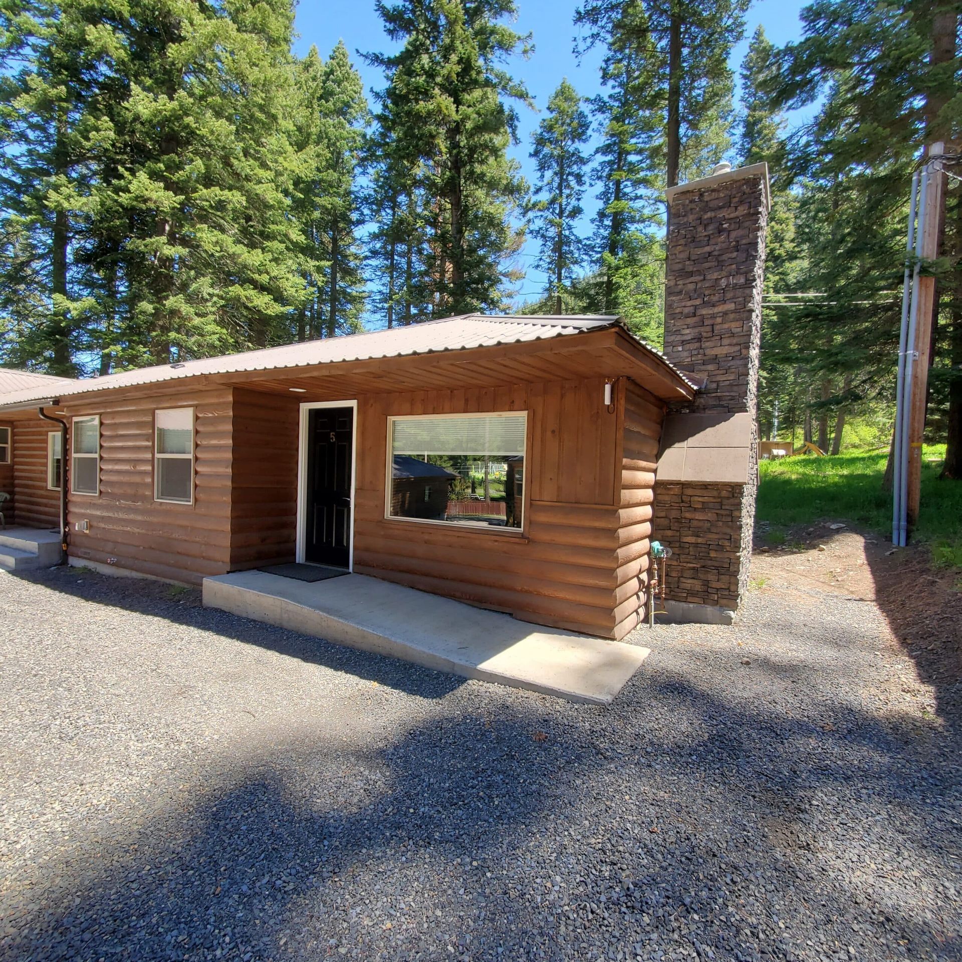 A small log cabin with a stone chimney in the woods