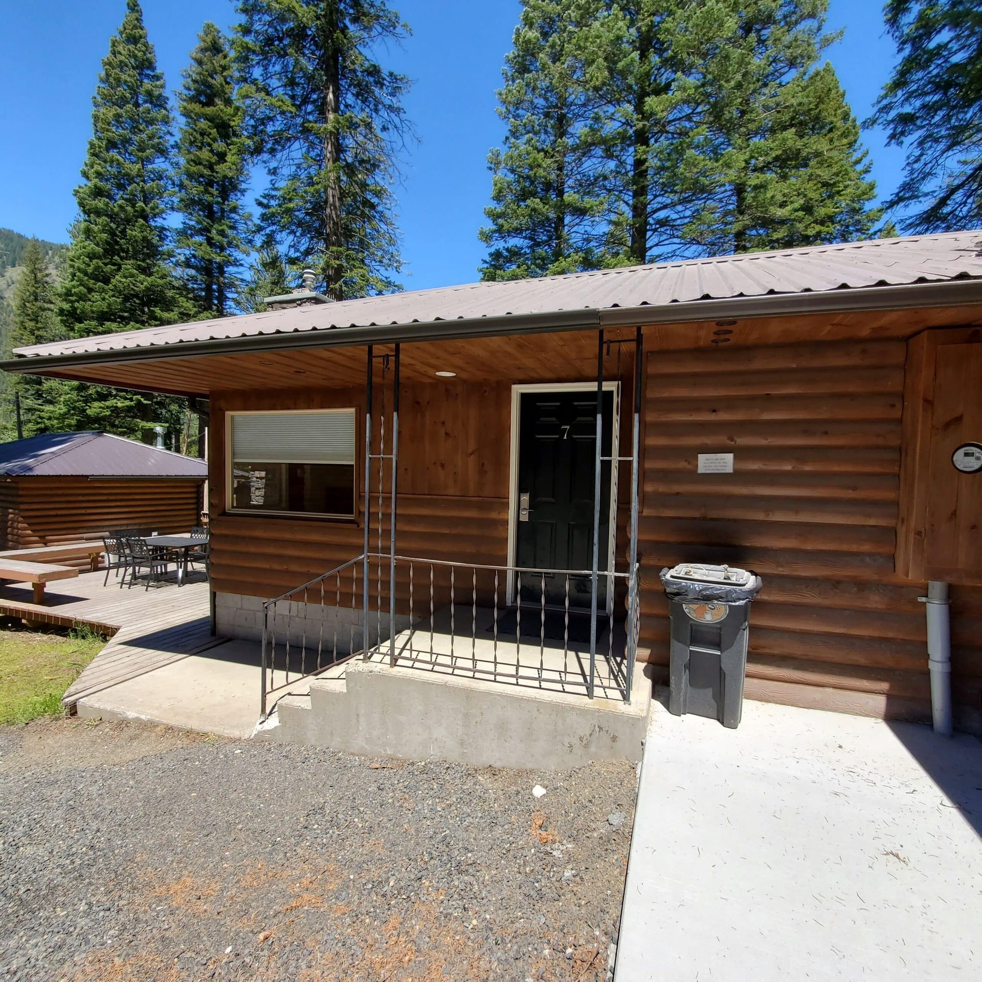 A log cabin with a trash can in front of it