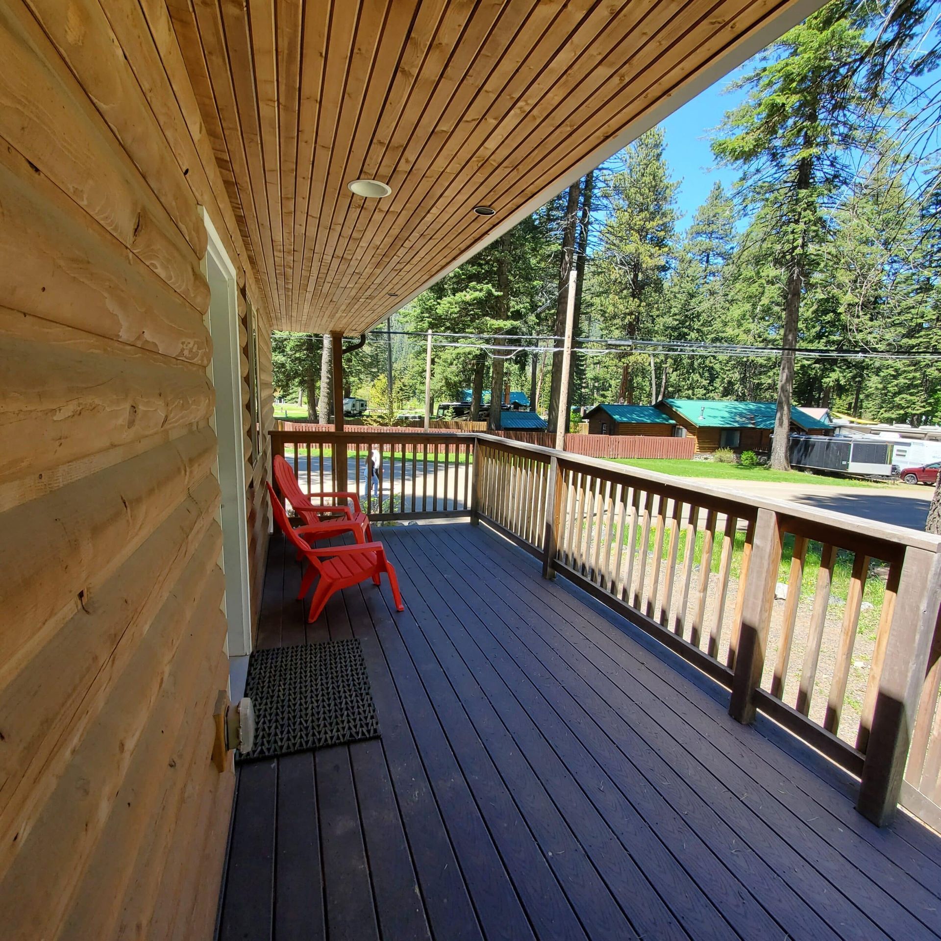A wooden deck with two red chairs on it