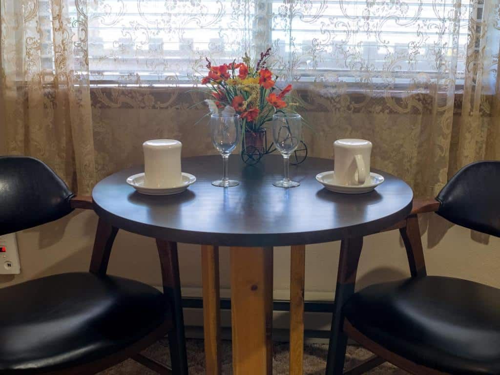 A table with two cups and two wine glasses on it in front of a window.
