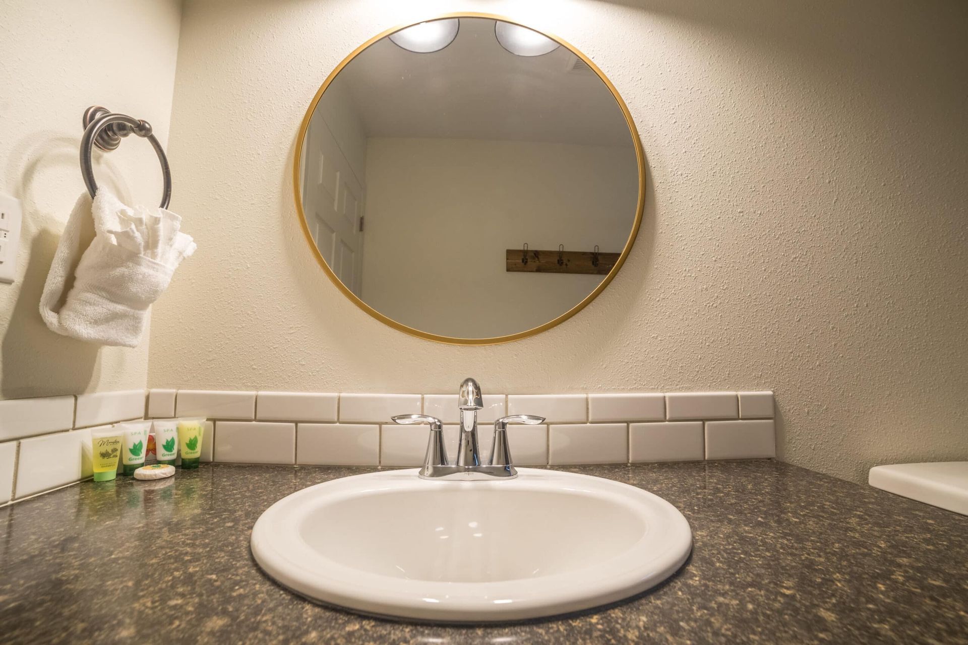 A bathroom sink with a round mirror above it.