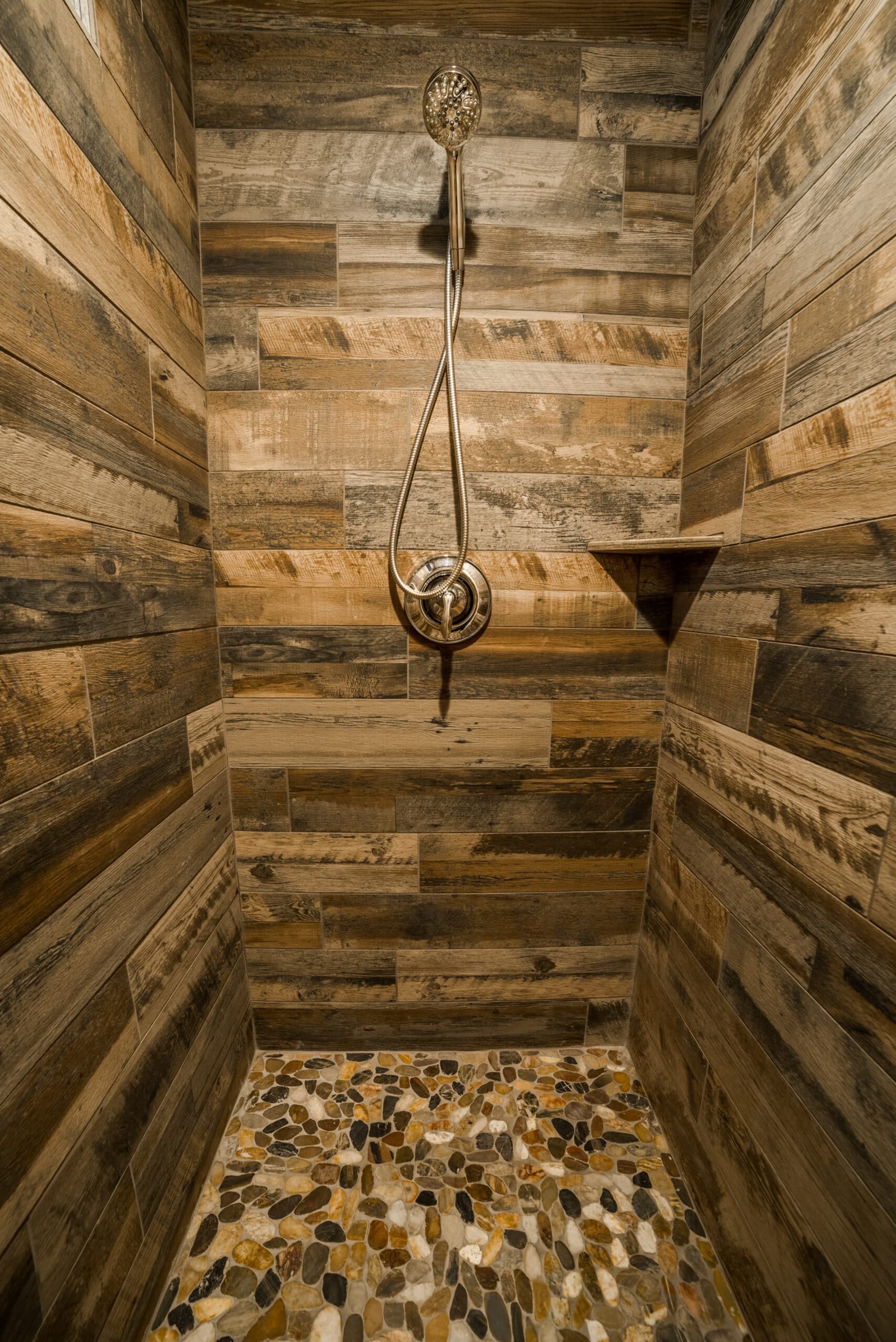 A shower with wooden walls and a pebble floor.