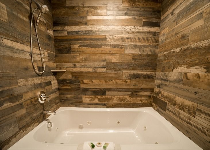 A bathroom with a jacuzzi tub and wooden walls.
