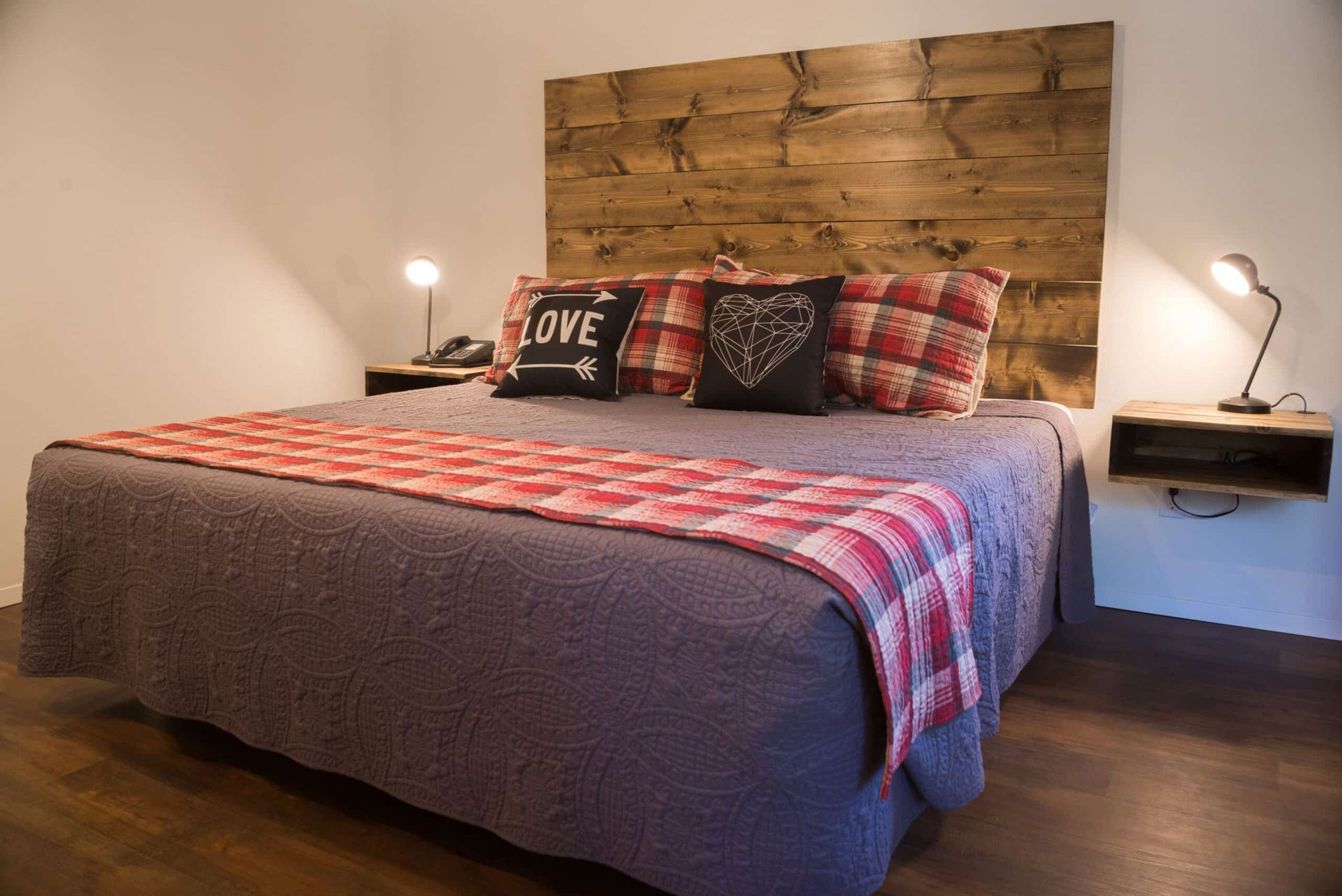 There is a bed with a wooden headboard and pillows on it.