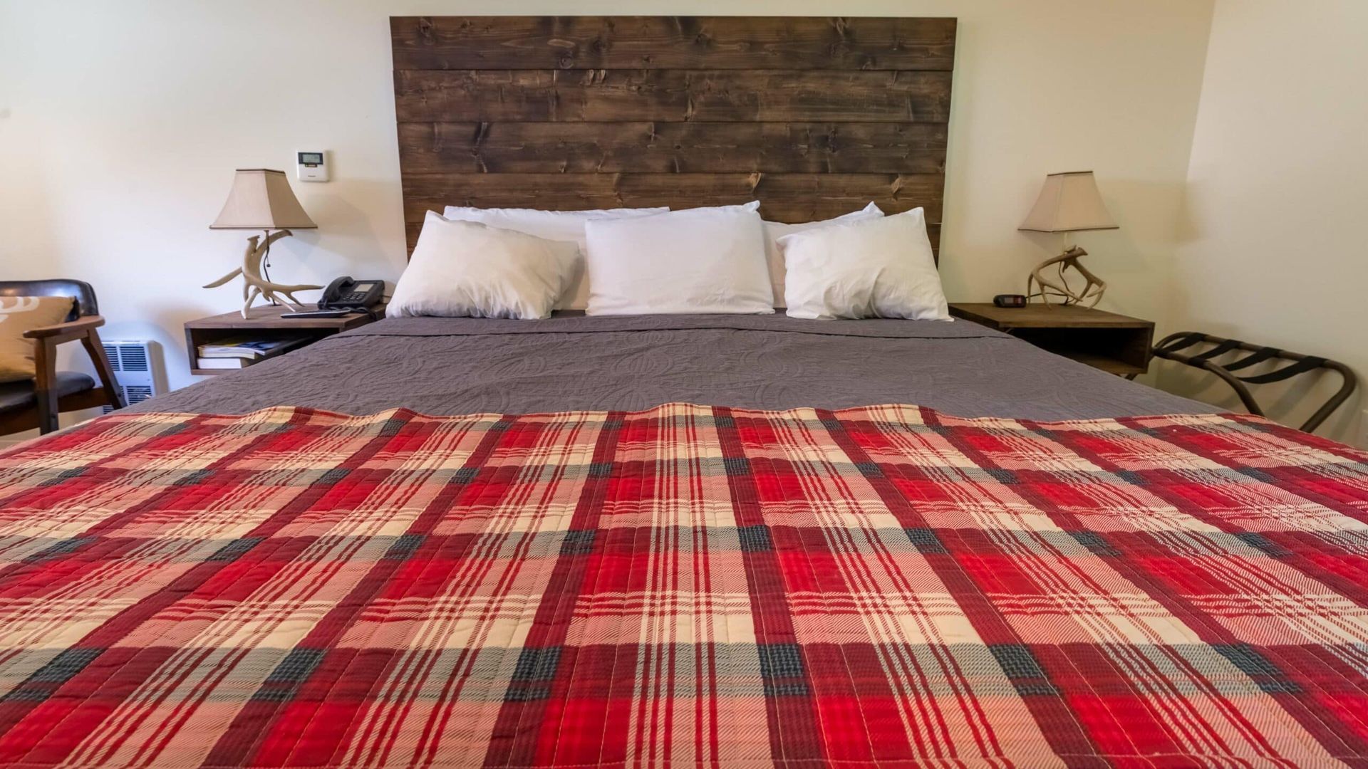 A bed with a plaid blanket on it in a hotel room.