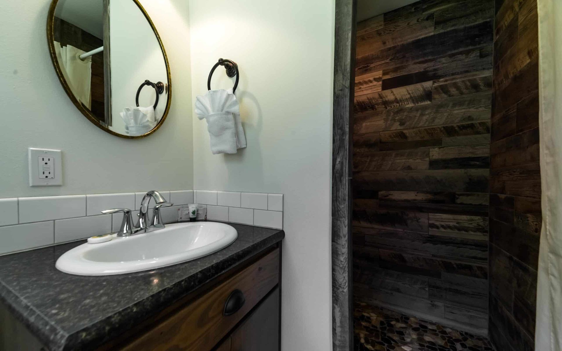 A bathroom with a sink , mirror and walk in shower.