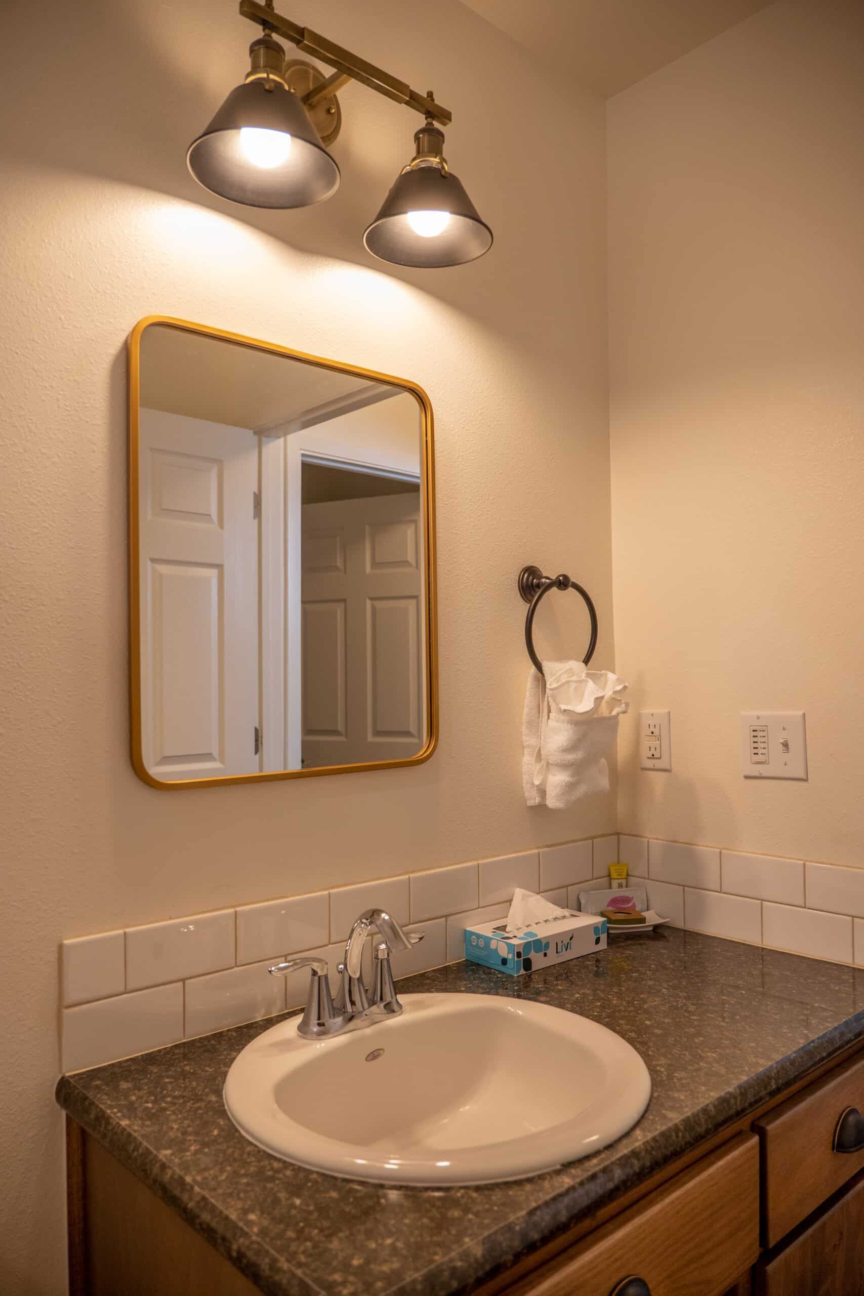 A bathroom with a sink , mirror and light fixture.