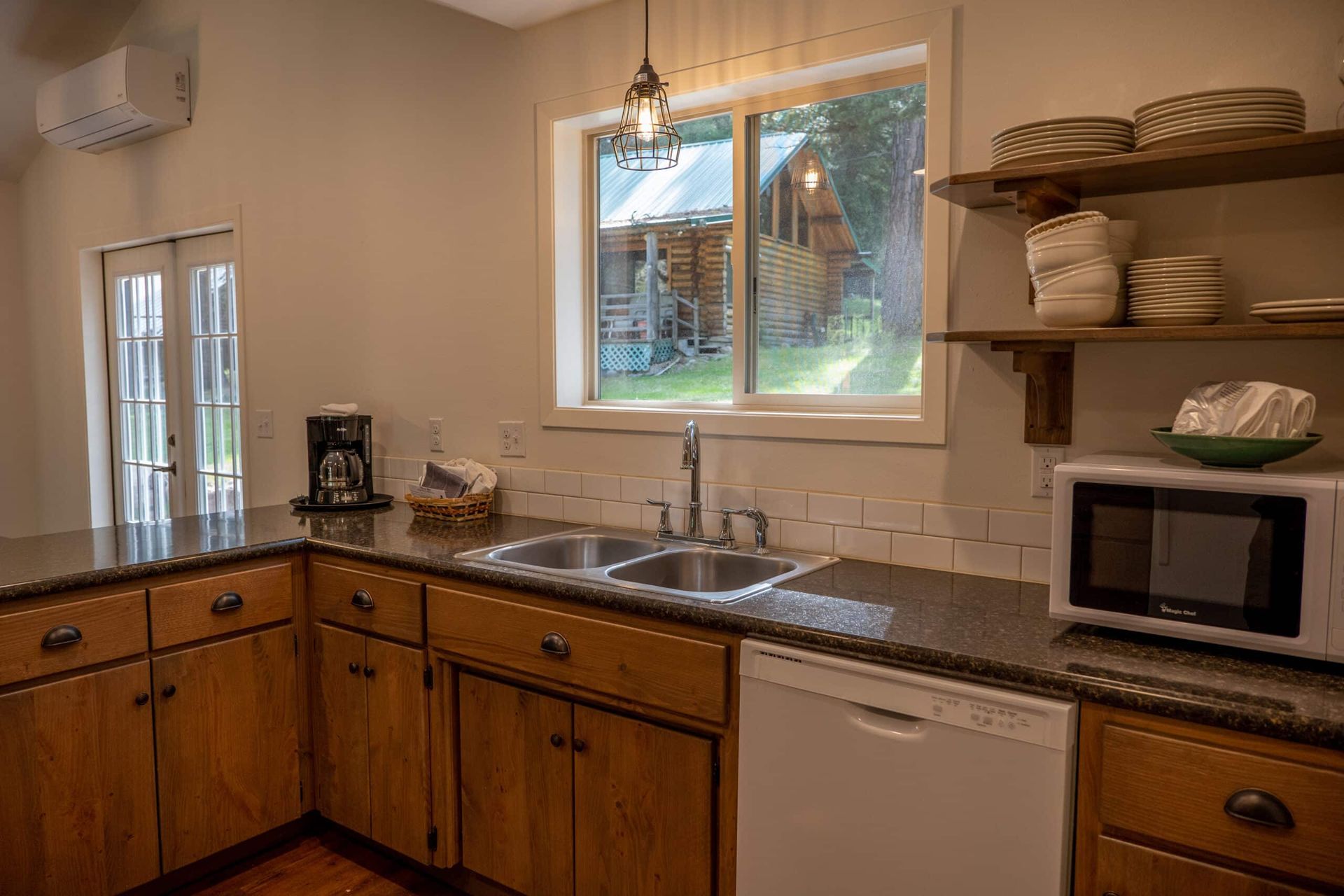 A kitchen with a sink , dishwasher , microwave and window.