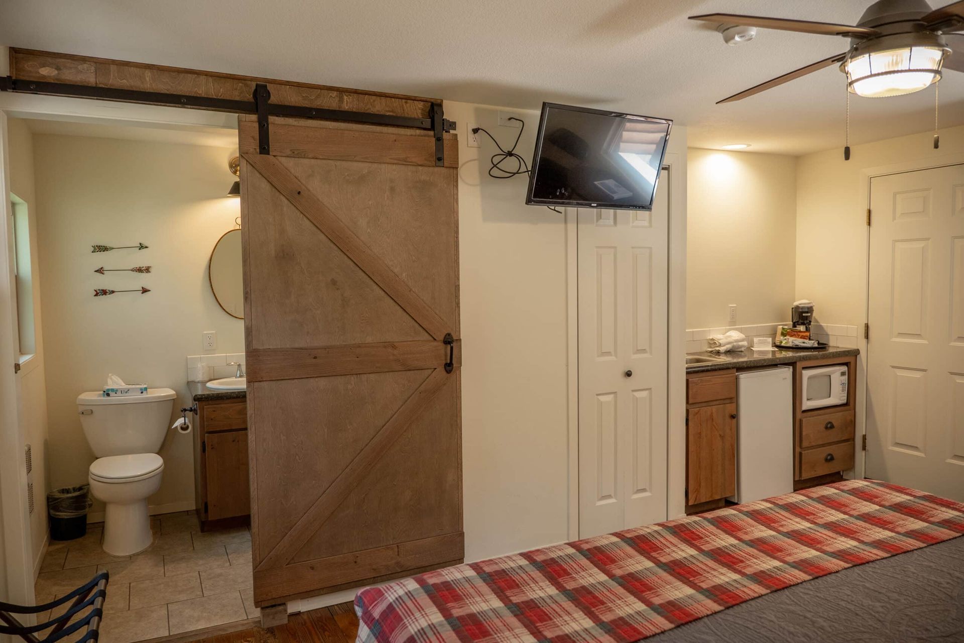 A bedroom with a sliding barn door leading to a bathroom.