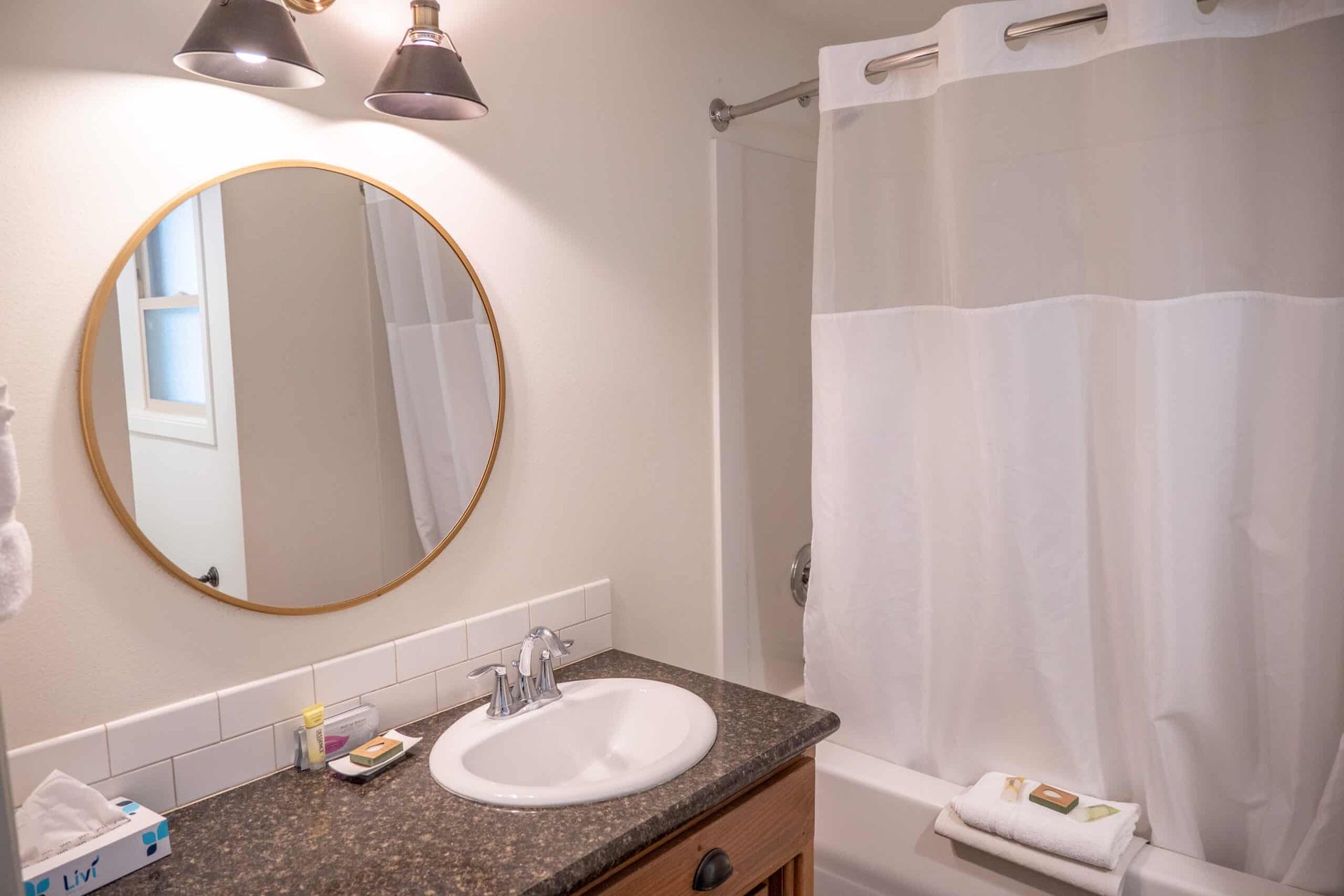 A bathroom with a sink , mirror and shower curtain.