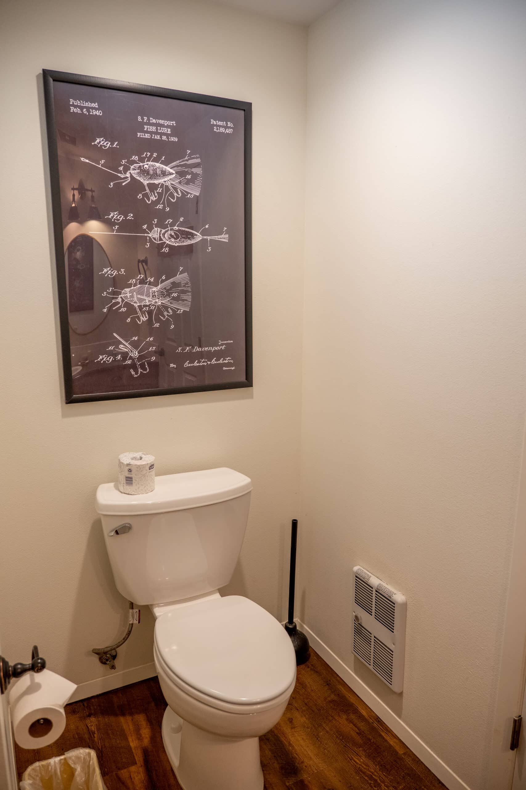 A toilet in a bathroom with a picture on the wall above it.