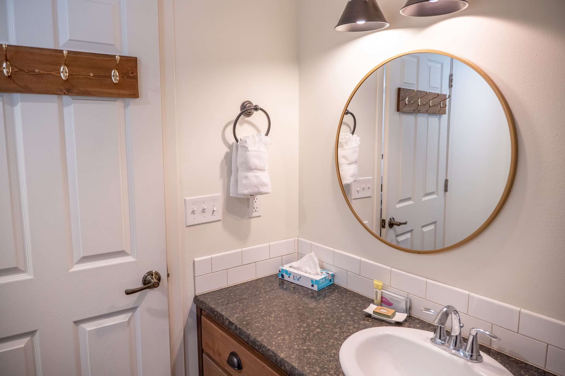 A bathroom with a sink and a round mirror.