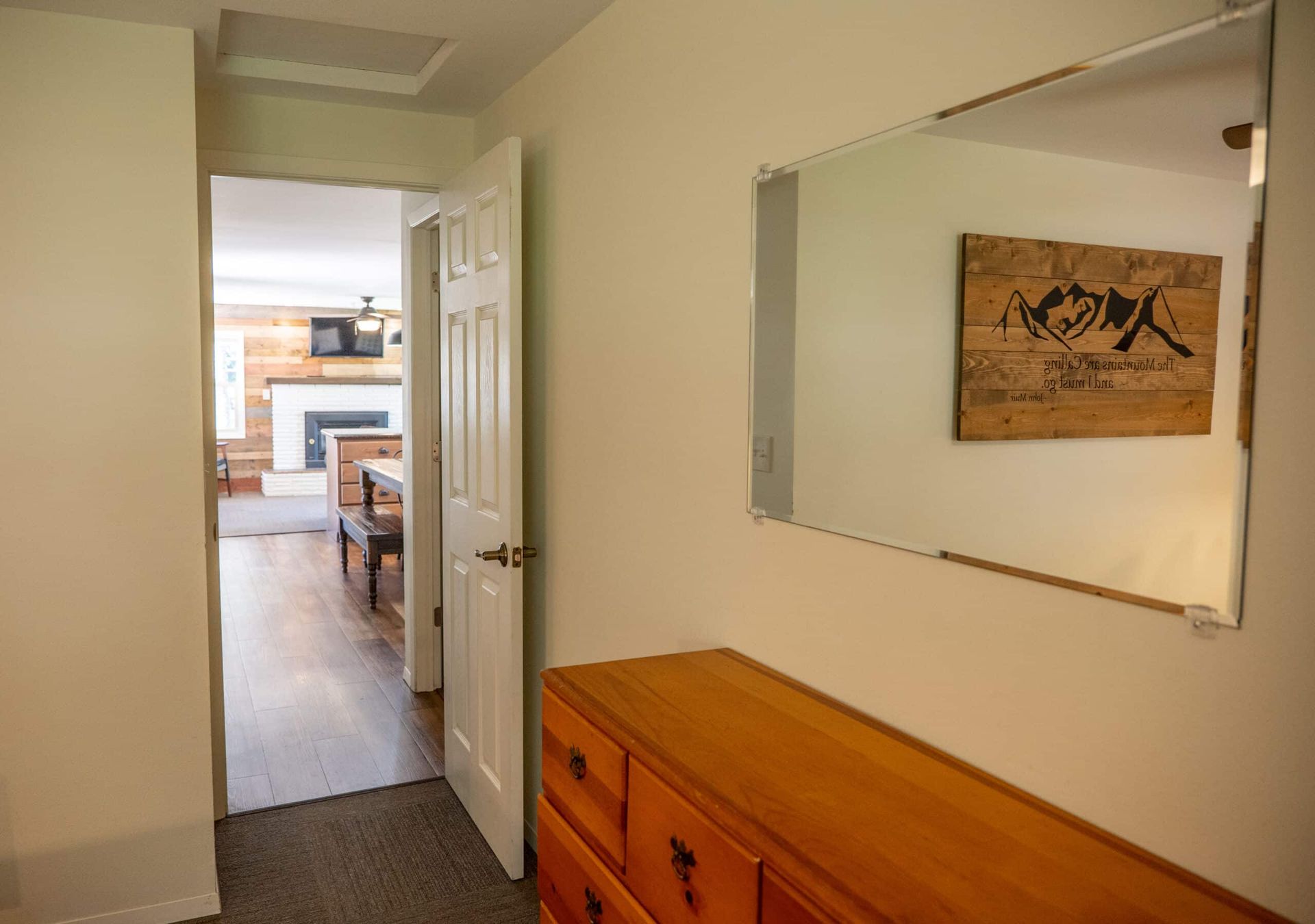 A hallway in a house with a dresser and a mirror.
