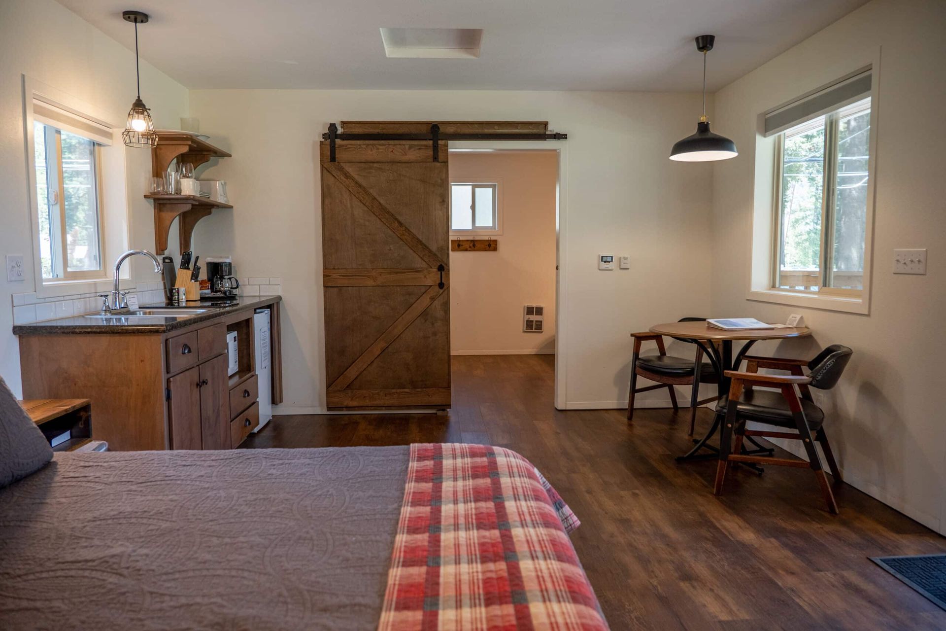 A bedroom with a bed , table , chairs and a sliding barn door.