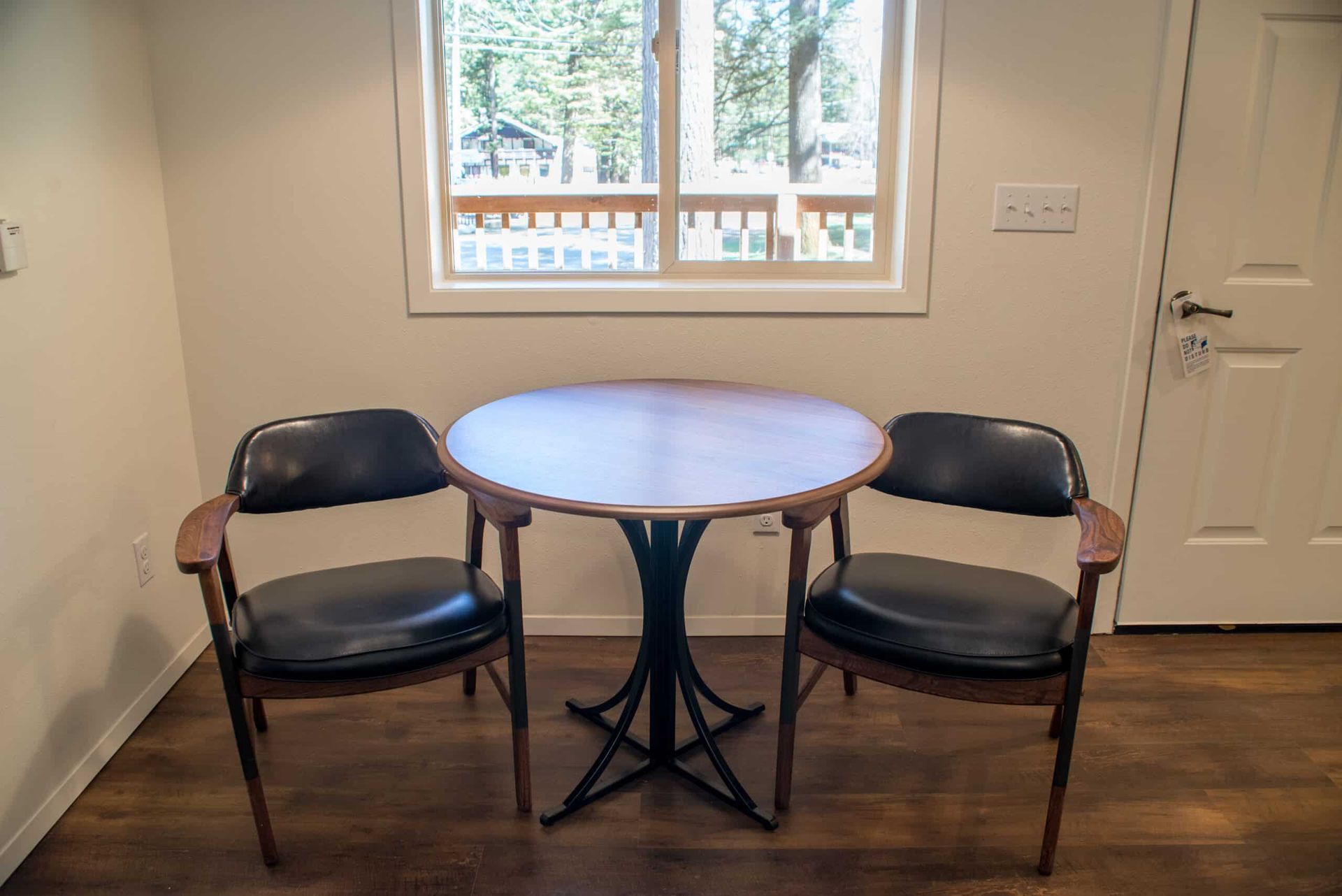A table and two chairs in a room with a window.