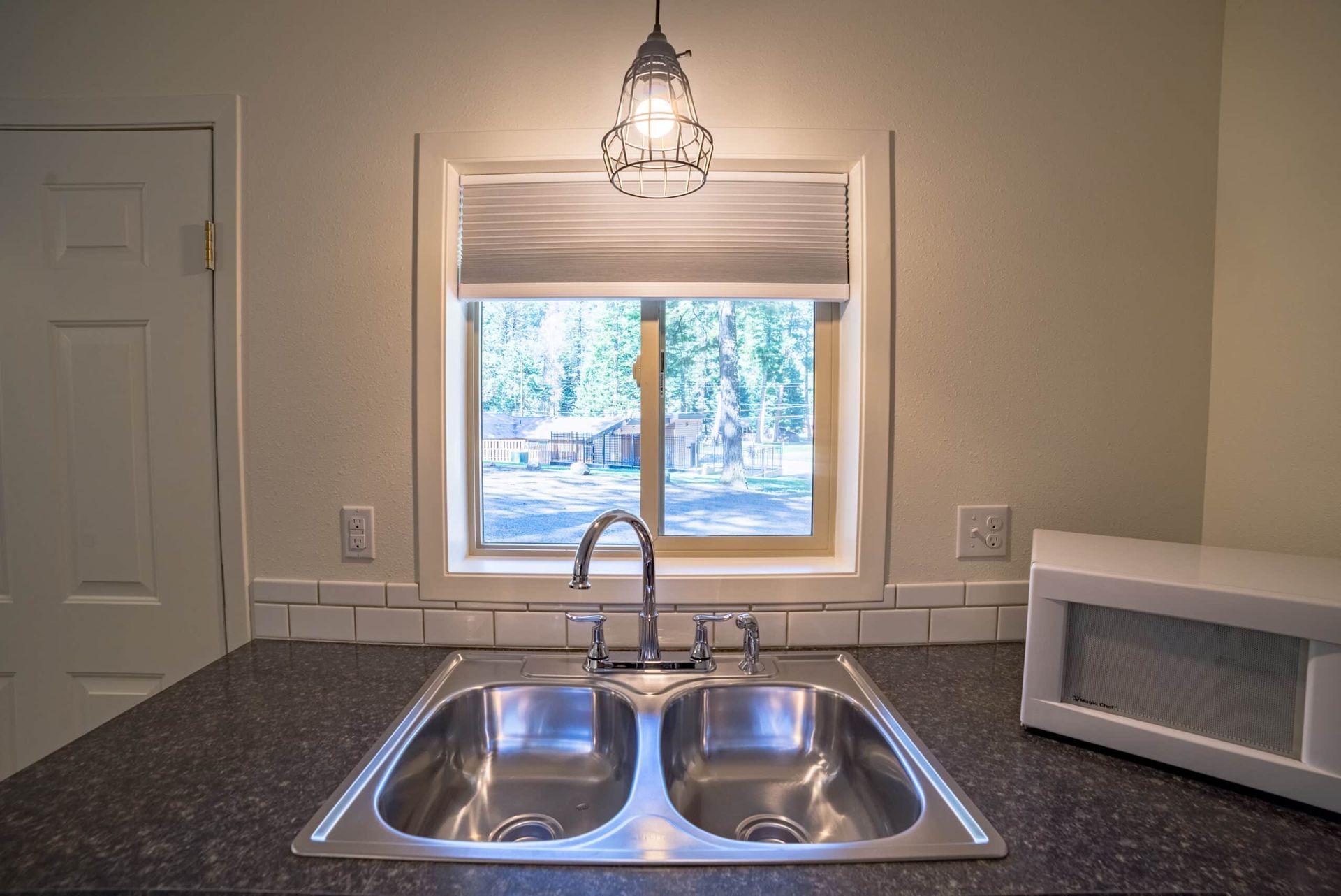 A kitchen sink with a window and a microwave