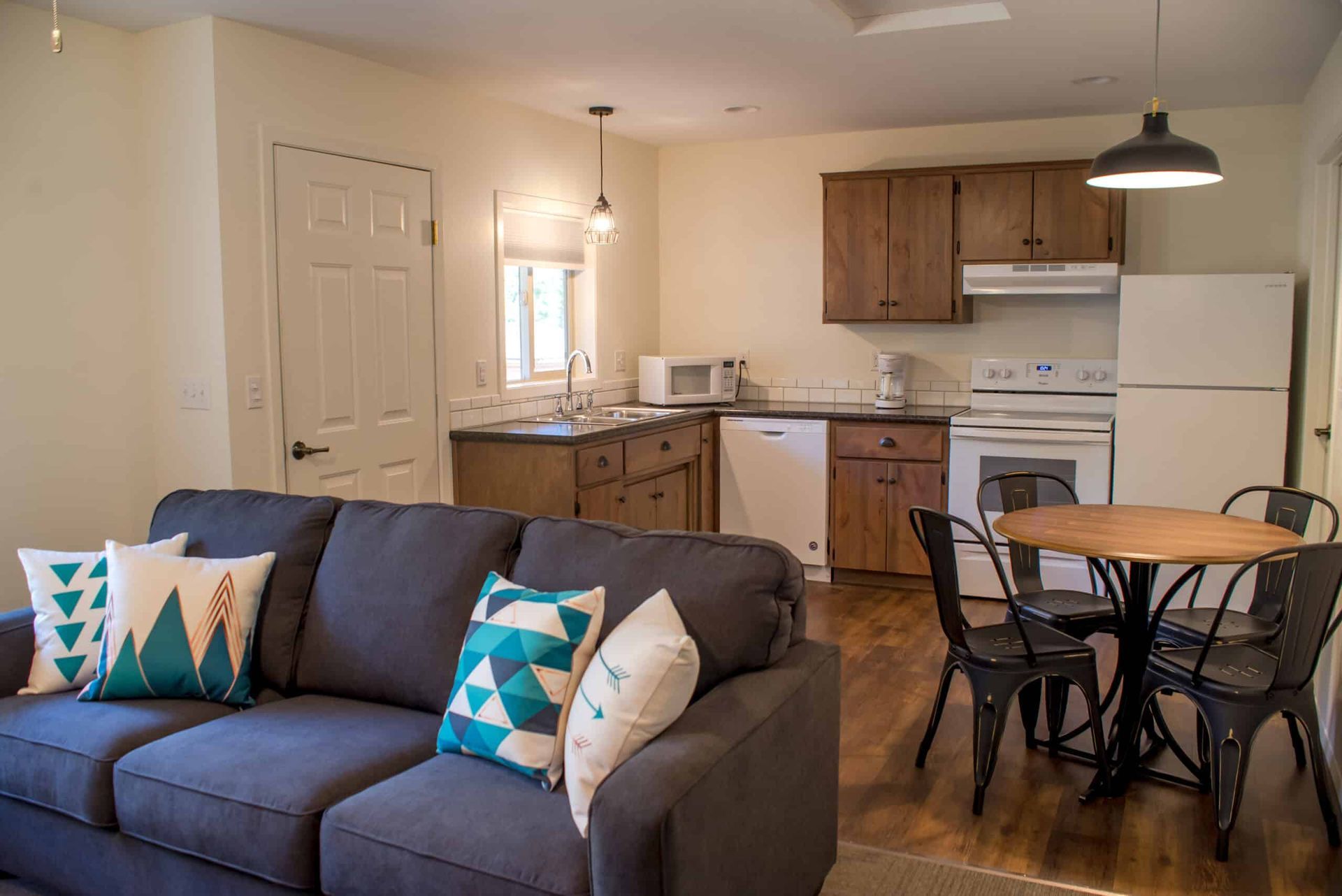 A living room with a couch , table , chairs and a kitchen.
