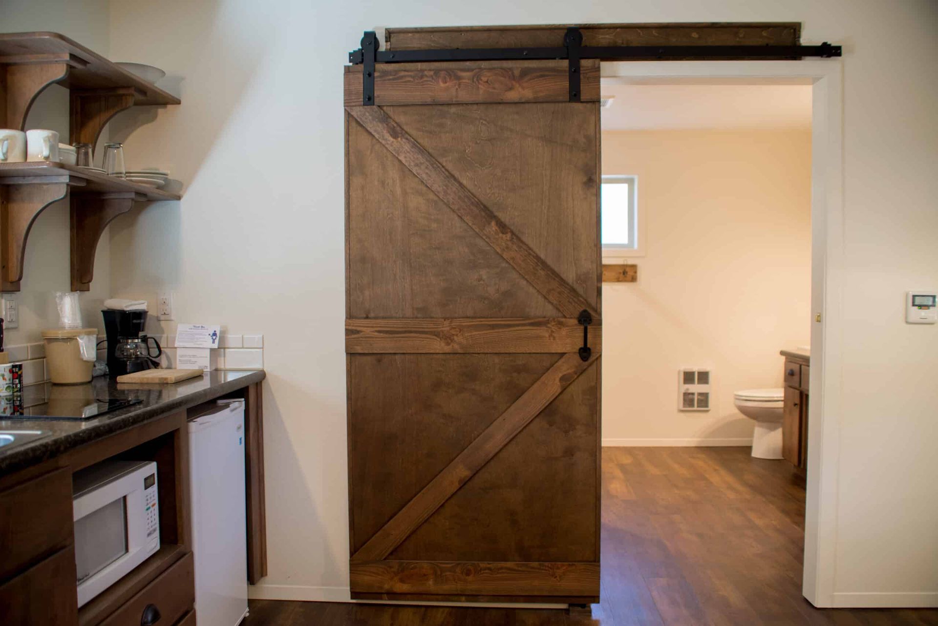 A kitchen with a sliding barn door leading to a bathroom.