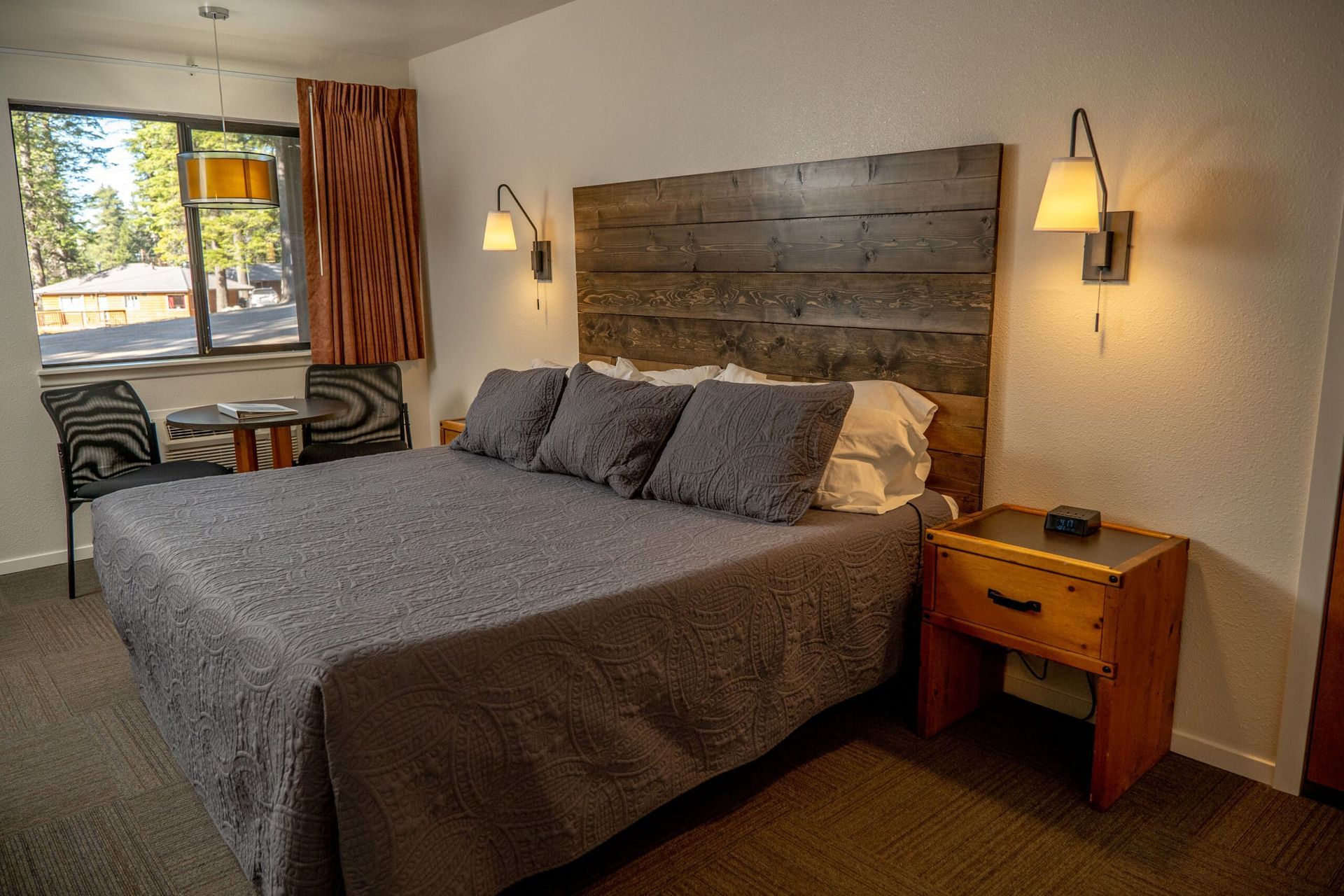 A hotel room with a king size bed and a wooden headboard