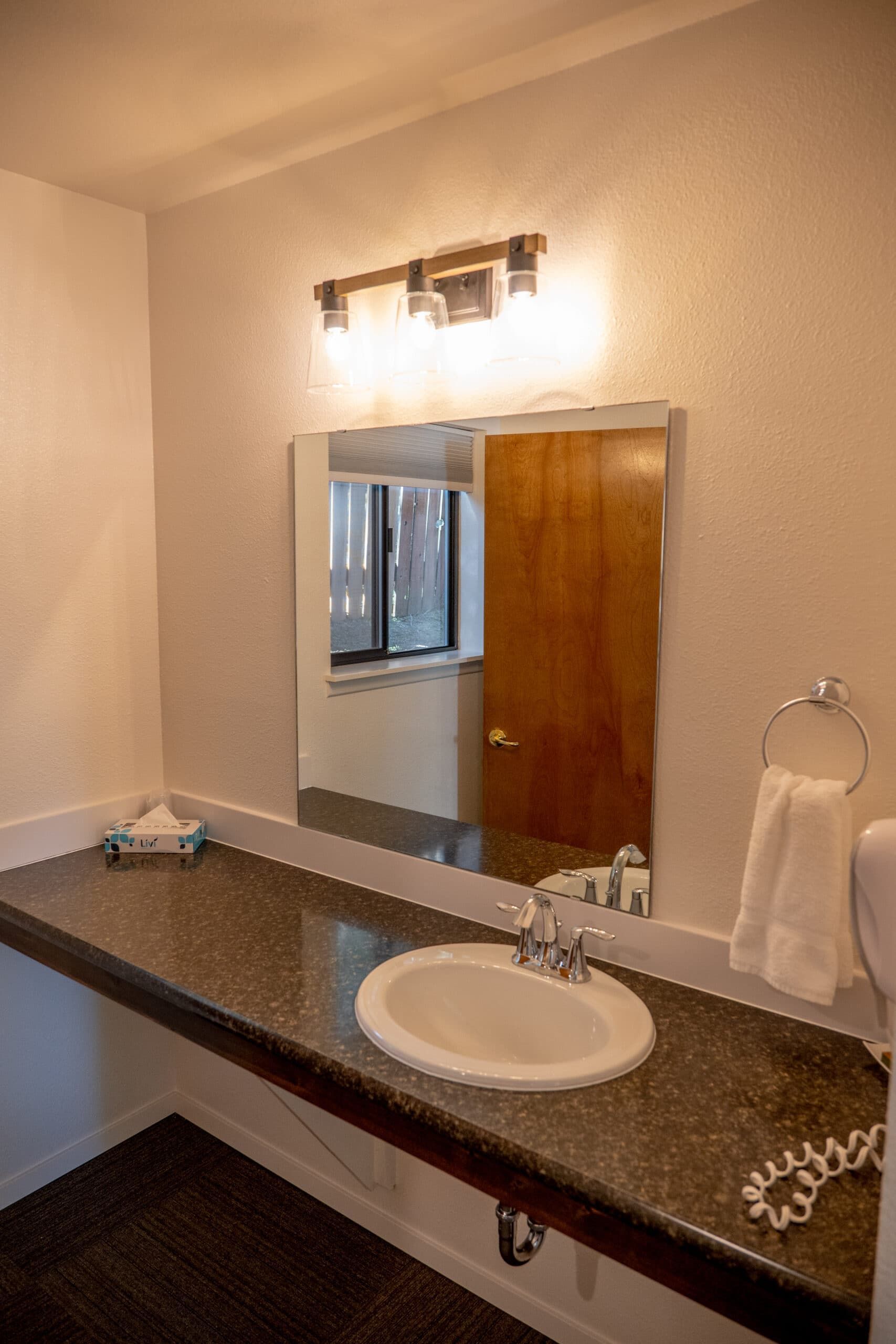 A bathroom with a sink , mirror and towel rack.