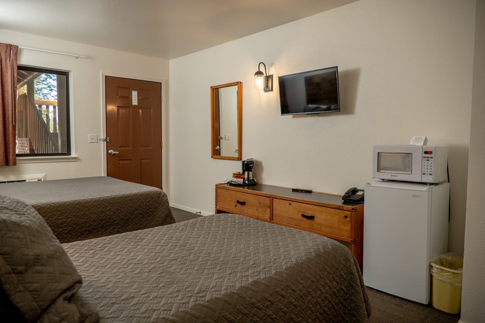 A hotel room with two beds , a microwave , and a television.