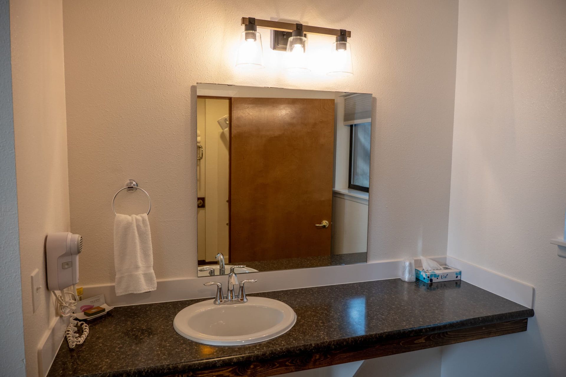 A bathroom with a sink , mirror and towel rack.