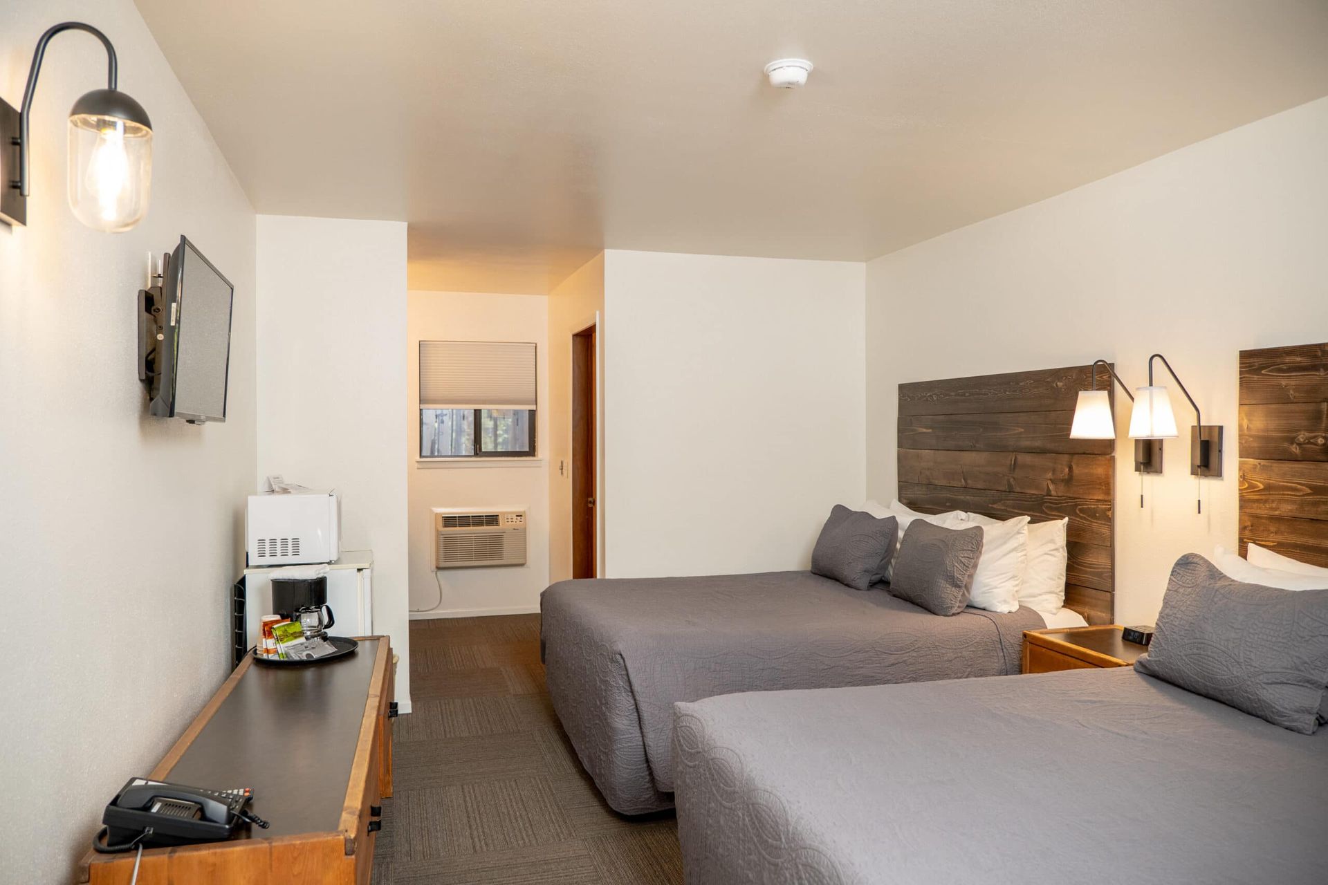 A hotel room with two beds , a desk , and a television.