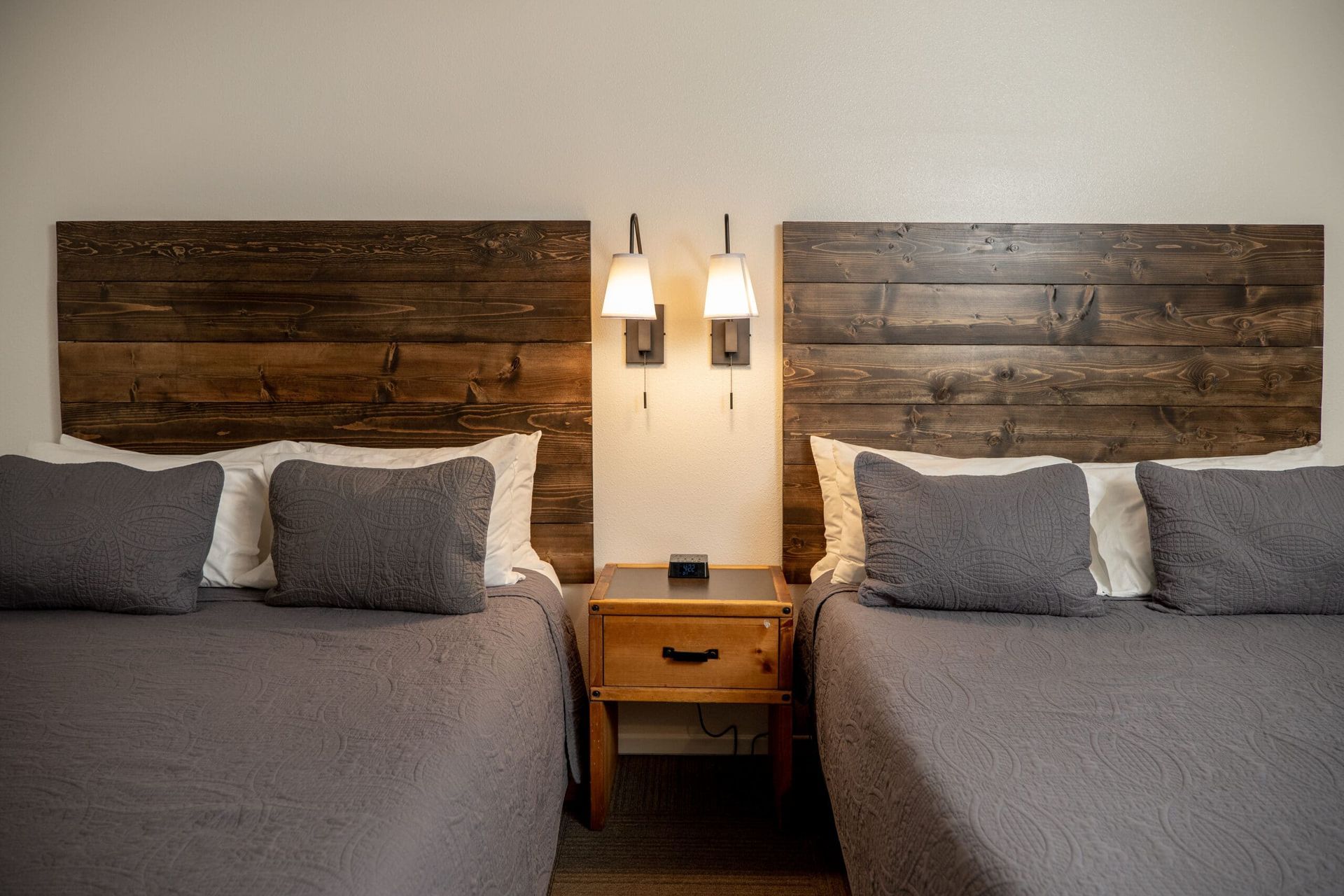 A hotel room with two beds and a nightstand.