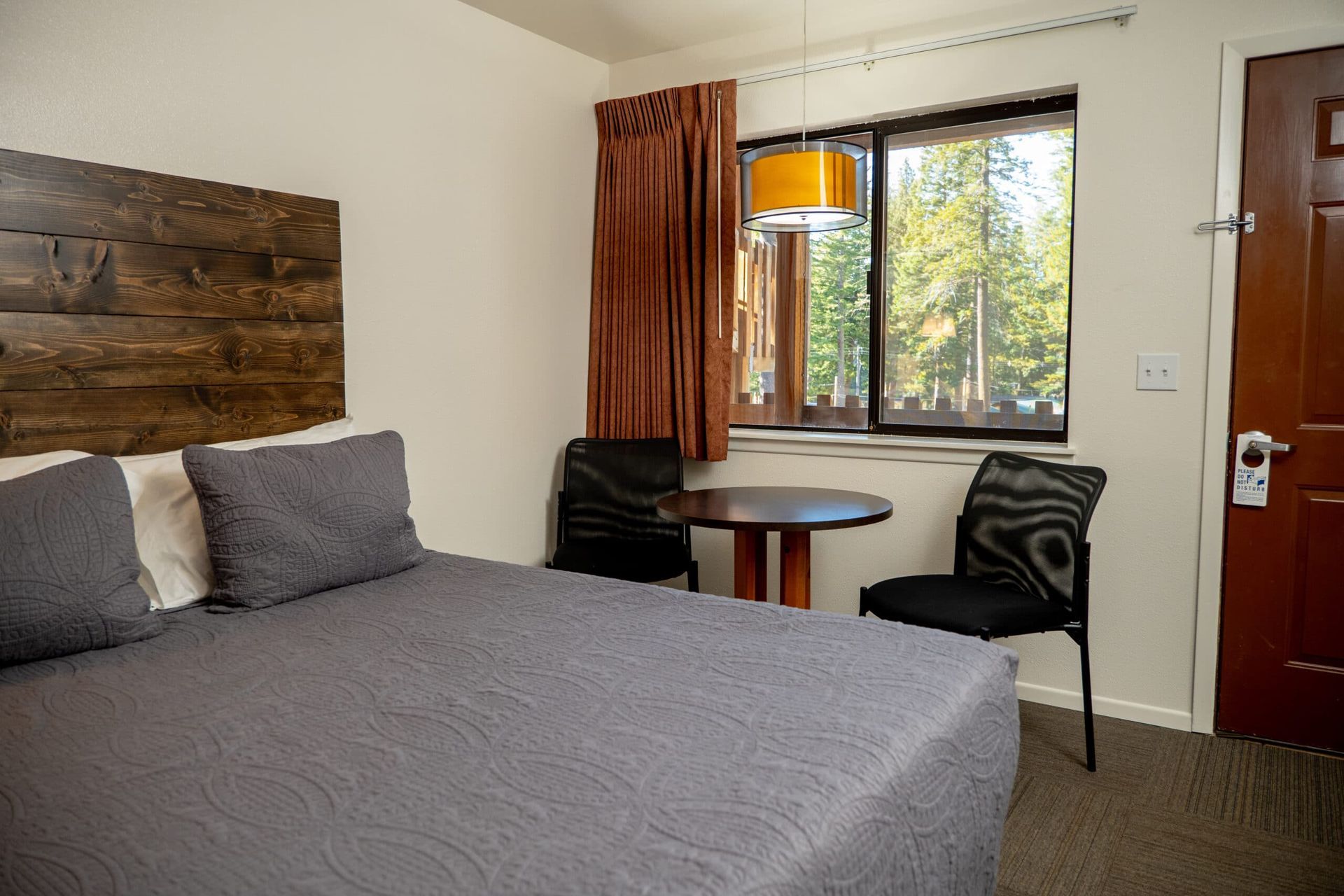 A hotel room with a bed , table and chairs.