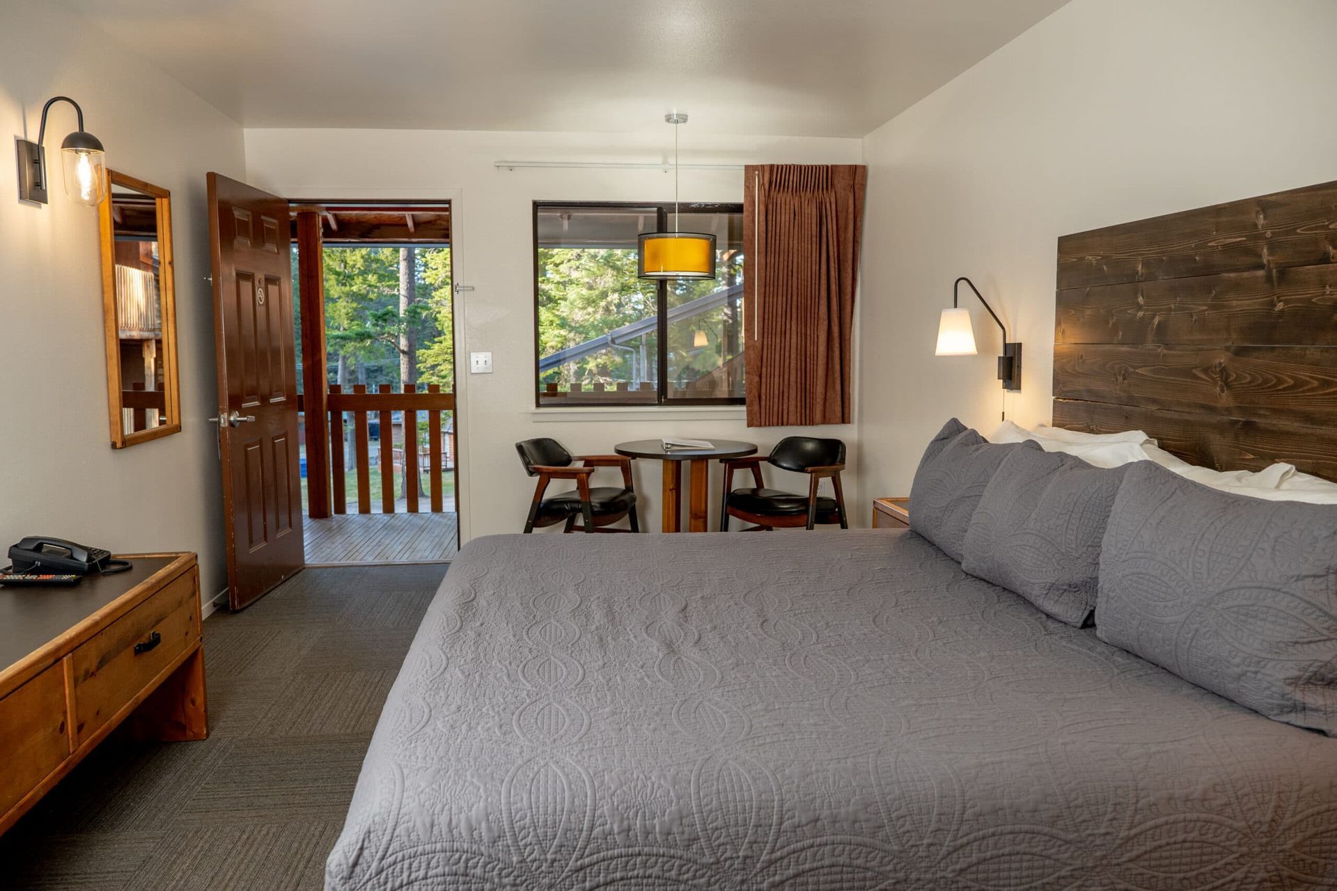 A hotel room with a king size bed , table and chairs.