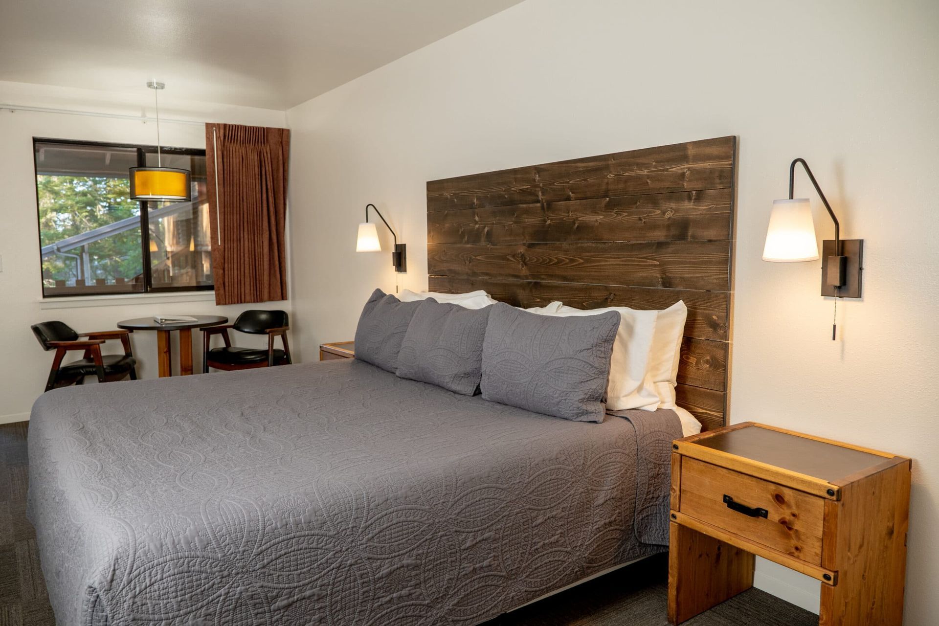 A hotel room with a king size bed and a wooden headboard.