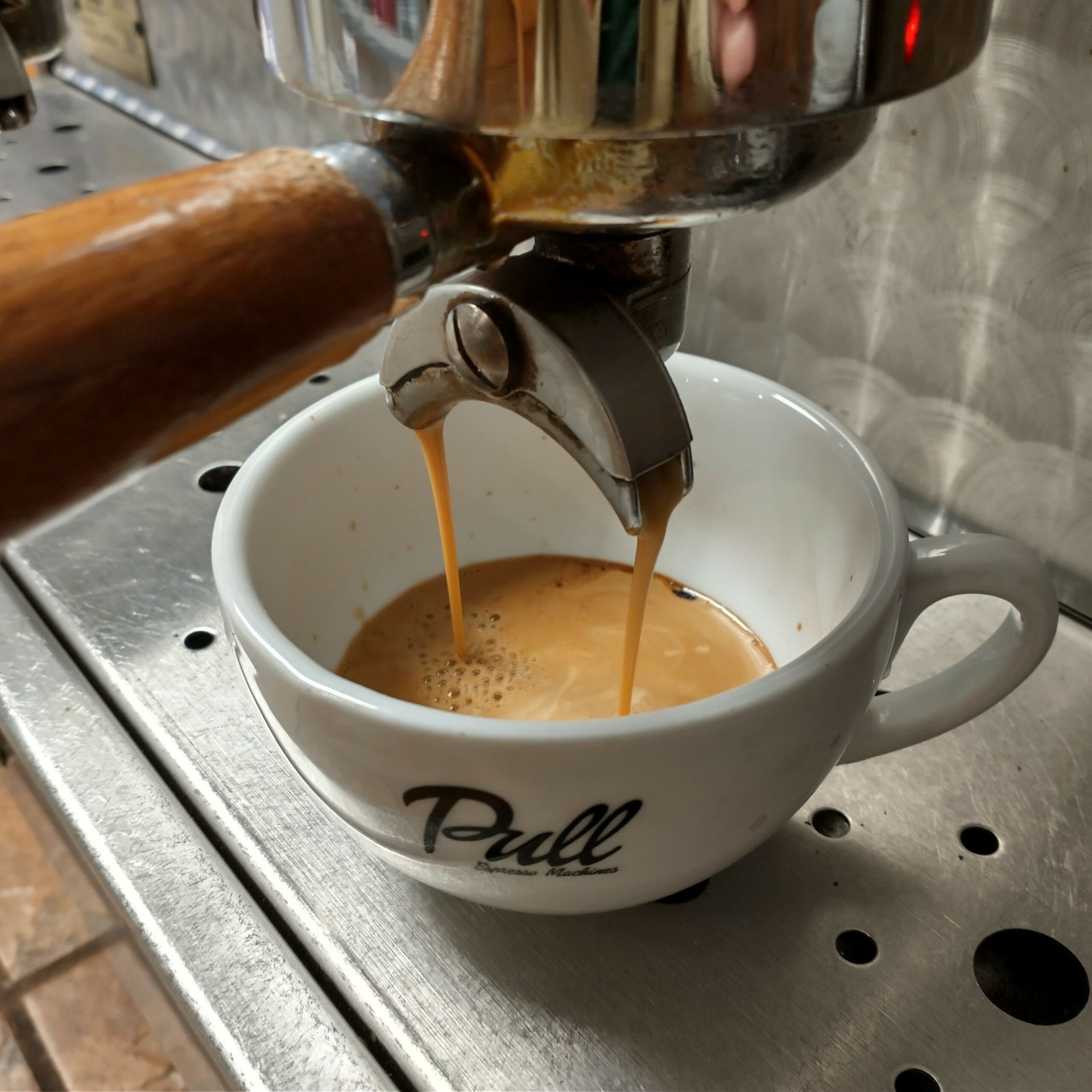 Coffee is being poured into a cup that says pull