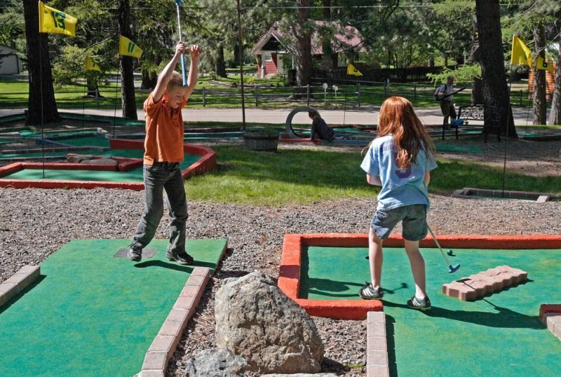 A boy and a girl are playing mini golf in a park