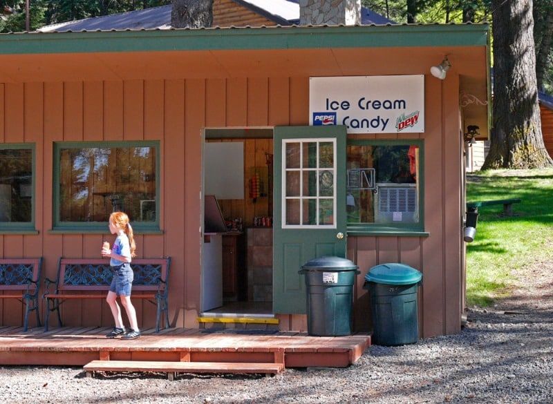 A little girl is standing outside of an ice cream shop.