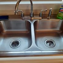 Double kitchen sink with stainless steel basins and chrome faucets under a countertop