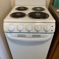 White electric stove with four coil burners and front control knobs in a kitchen.