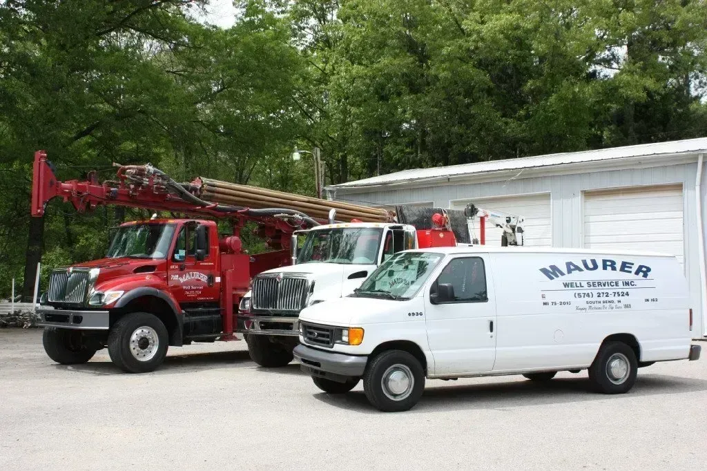 Three trucks and a van are parked in front of a building that says maurer