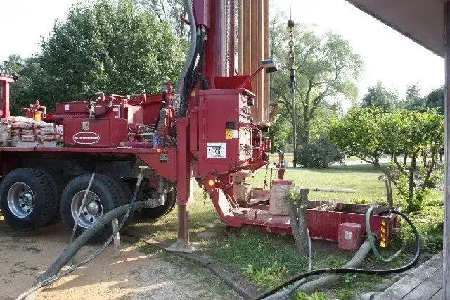 A red truck with a hose attached to it is parked in front of a house. A red truck with a hose attached to it is parked in front of a house.