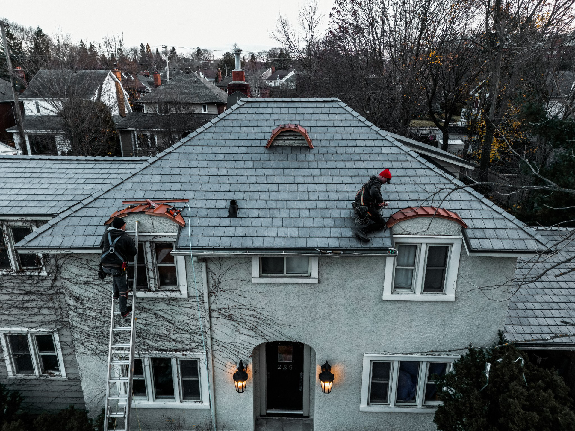 Aerial view of a long building with a black roof, construction site with a pool, and heavy machinery nearby.