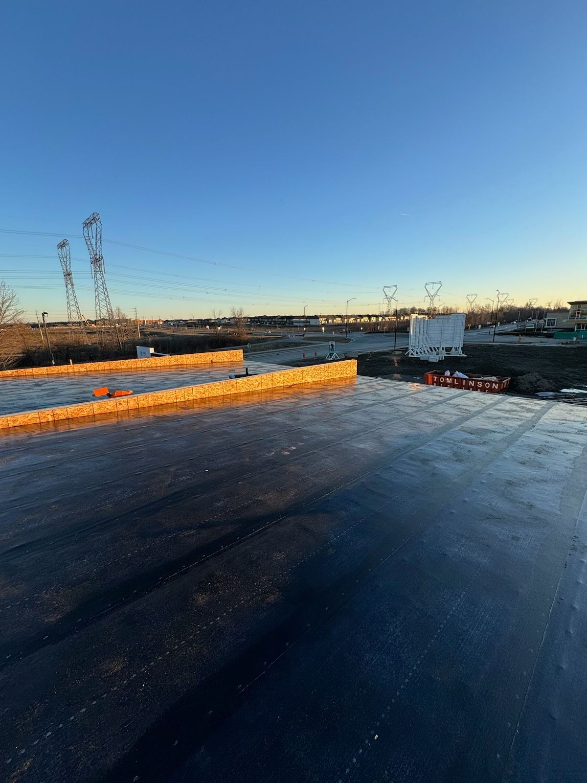 Construction site with black surface and wood frames under a clear blue sky.