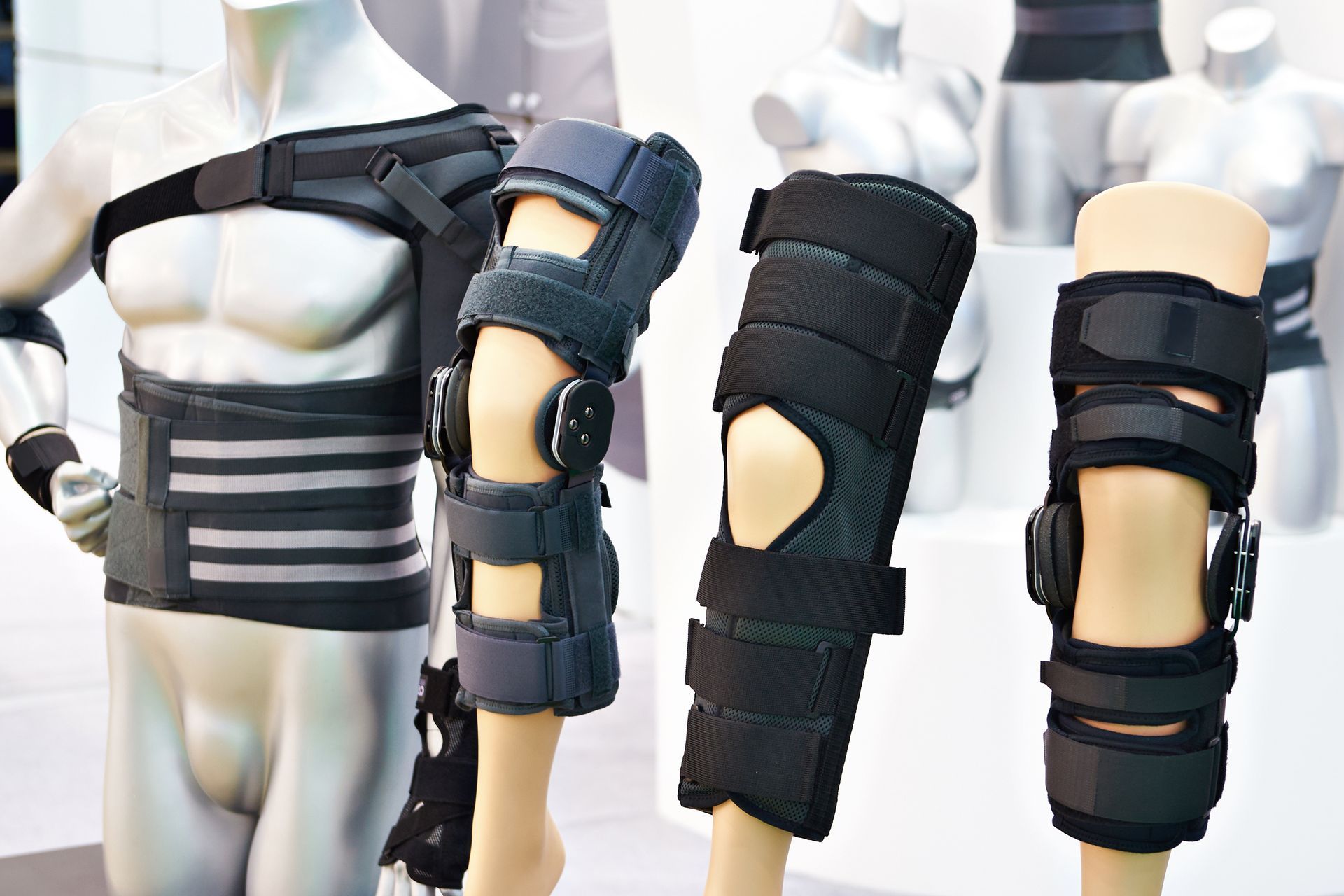 Mannequin displaying various orthopedic braces: shoulder, back, knee, and ankle.