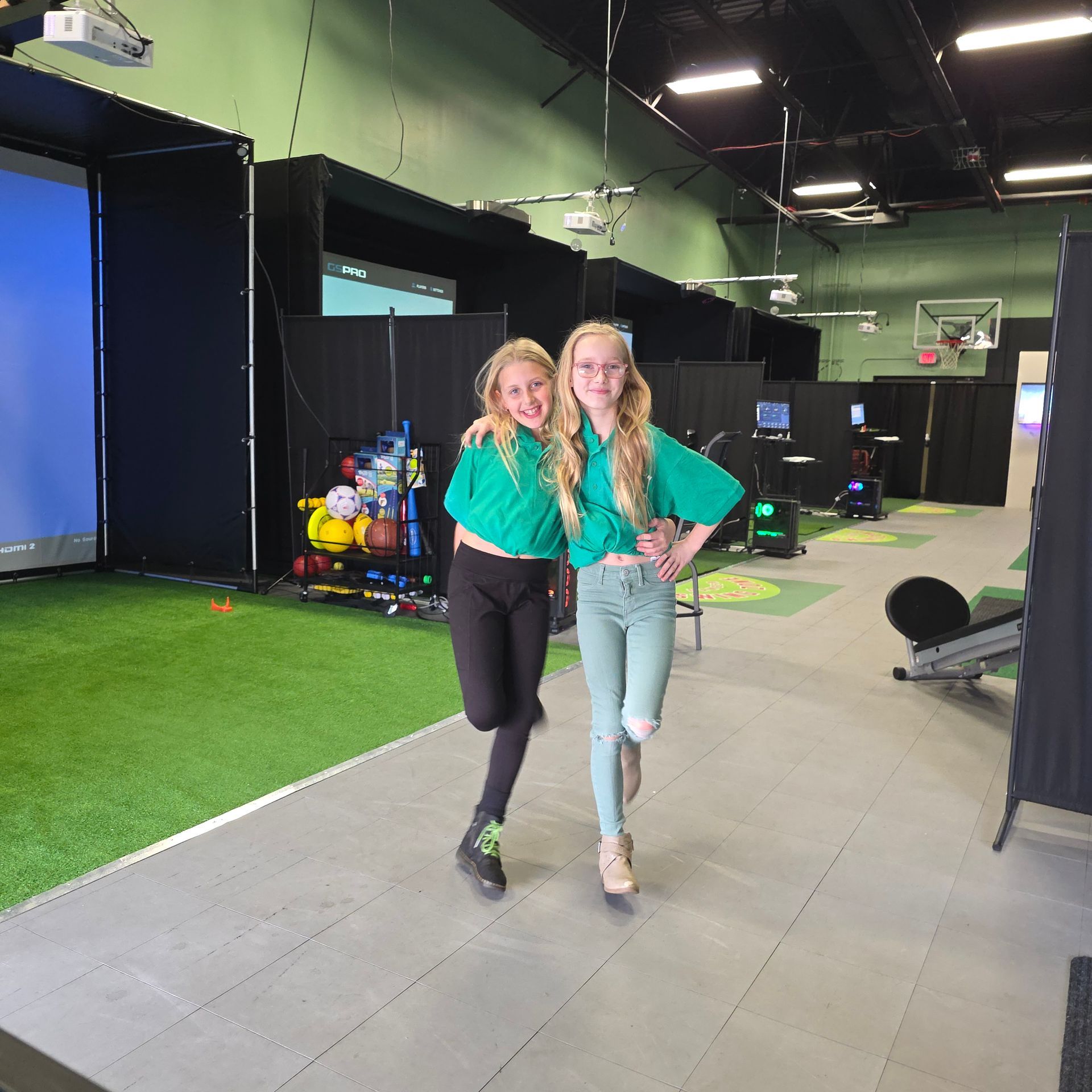 Golfer putting a golf ball on green turf, indoors; screen in background.