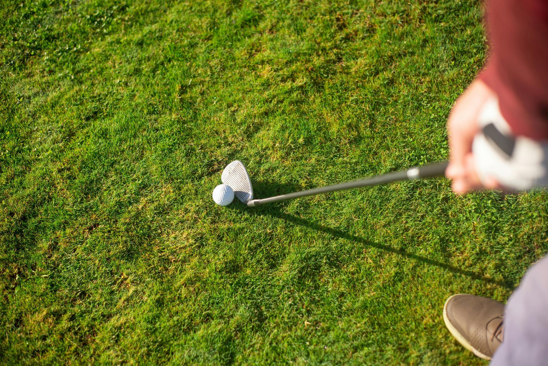 Golfer about to hit golf ball with club on green grass.