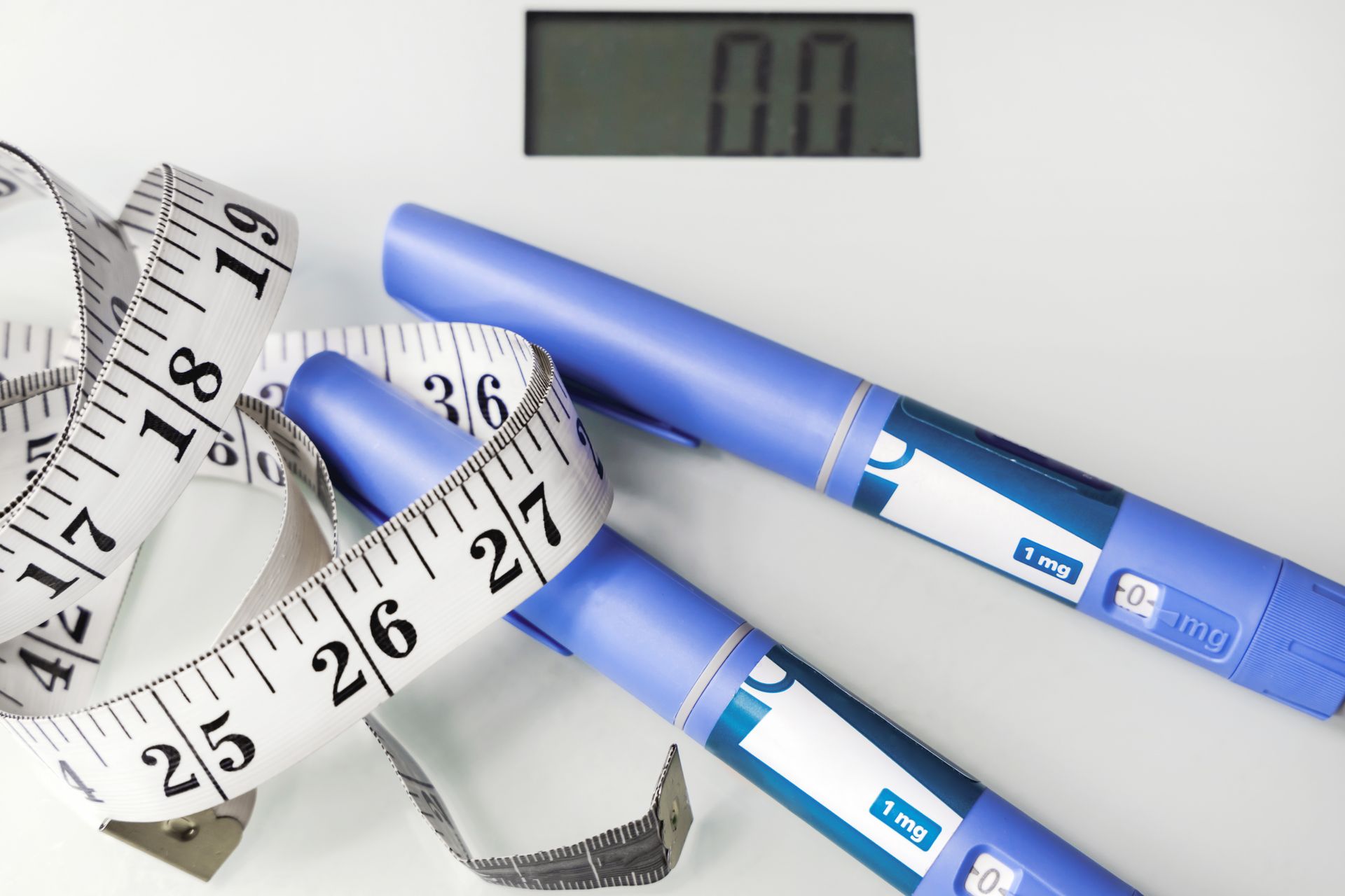 Two blue pregnancy test sticks with a measuring tape and digital scale display on a white background