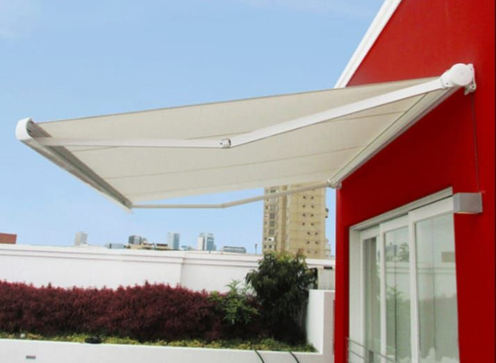 Un toldo retráctil blanco se extendía desde un edificio rojo. El horizonte de la ciudad al fondo.