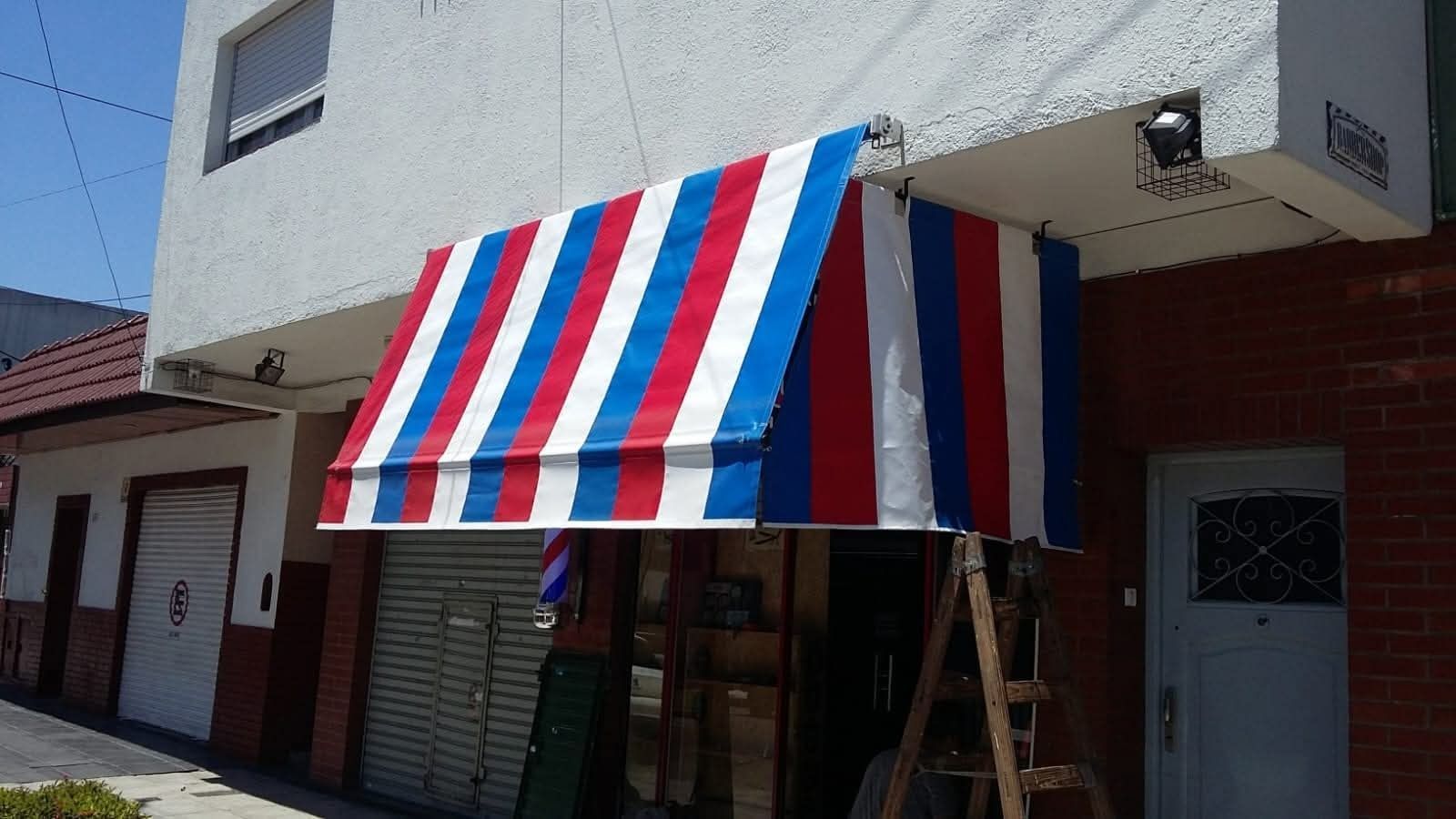 Toldo de rayas rojas, blancas y azules sobre la entrada de una tienda.