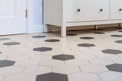 White and dark gray hexagonal tile floor with white cabinet and door.